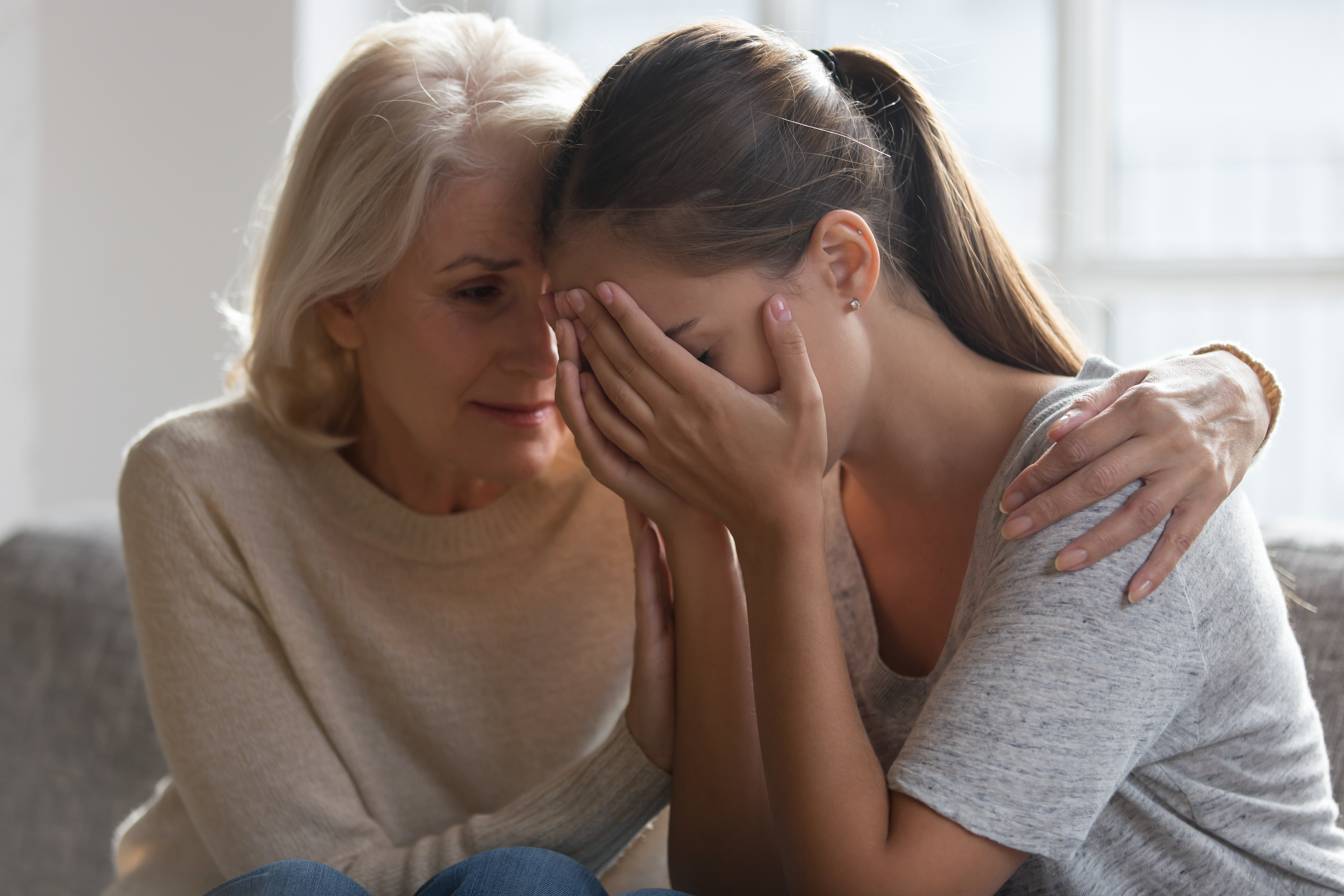 An older woman consoling a young girl | Source: Shutterstock