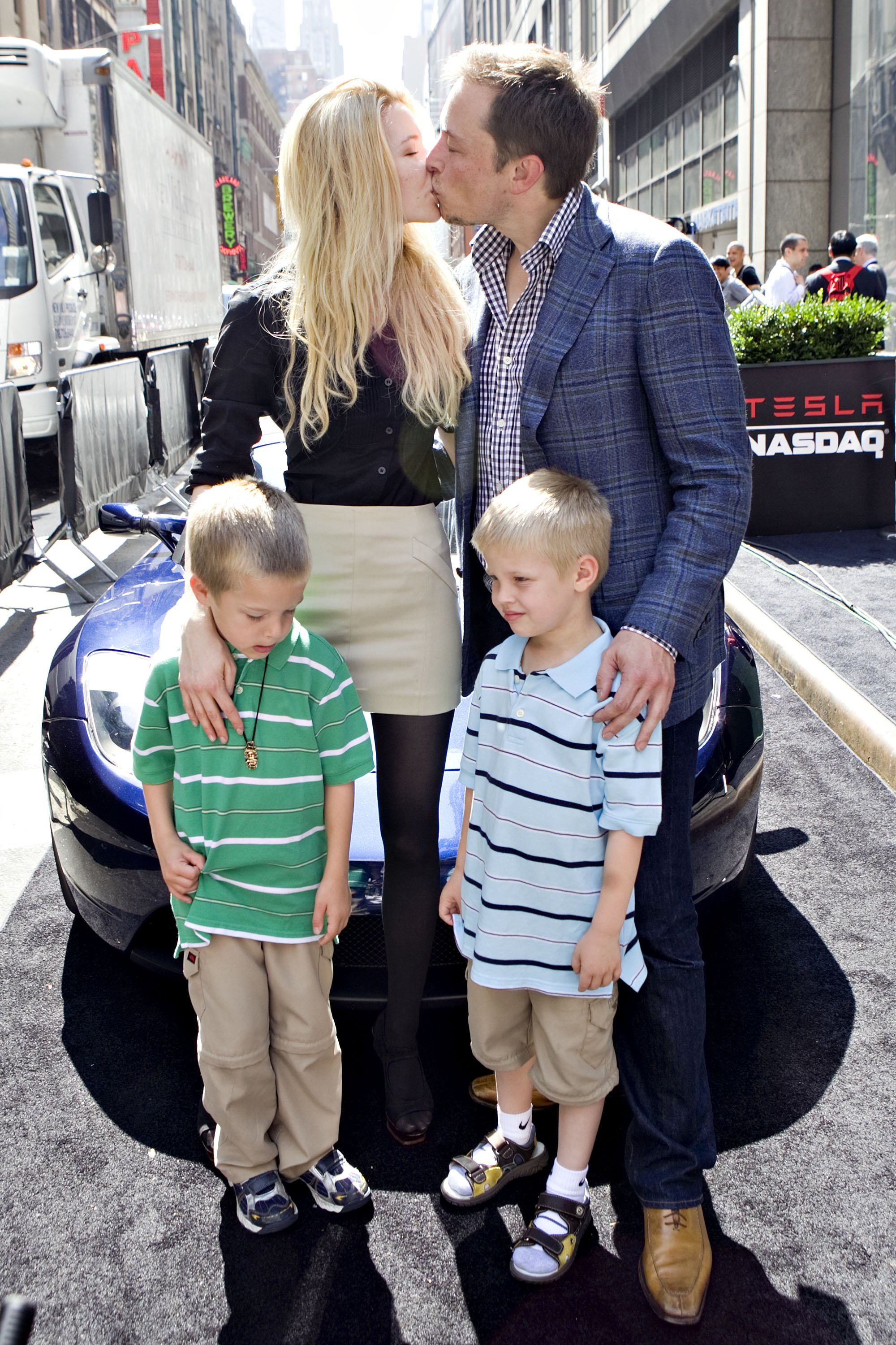 Elon Musk, chairman and chief executive officer of Tesla Motors, kisses his fiancee Talulah Riley as they stand with Musk's twin boys Griffin, left, and Xavier, outside the Nasdaq Marketsite in New York, U.S., on Tuesday, June 29, 2010. | Source: Getty Images