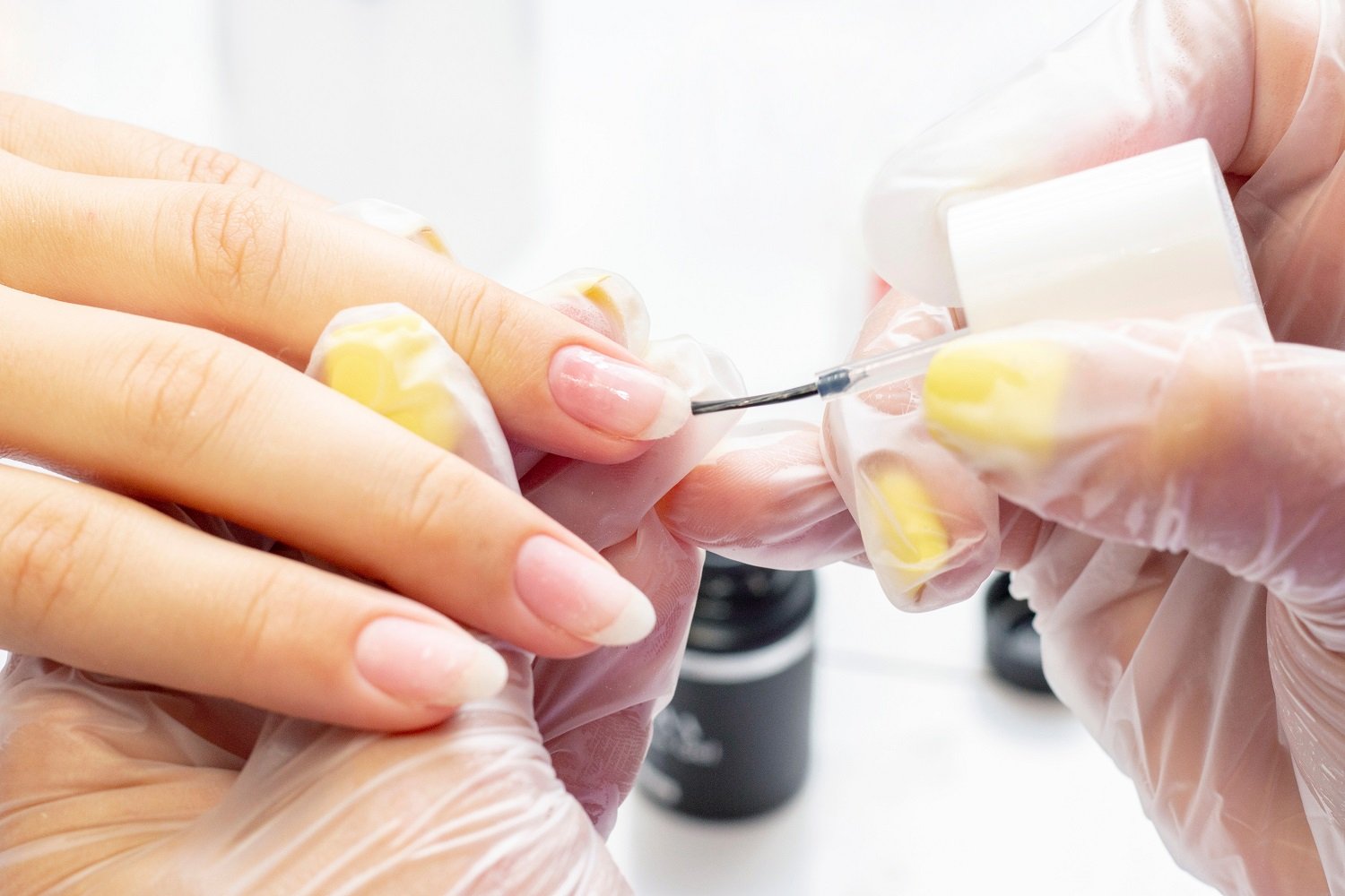 Profesional manicurista aplicando esmalte base a las uñas de una mujer. | Foto: Shutterstock Profesional manicurista aplicando esmalte base a las uñas de una mujer. | Foto: Shutterstock