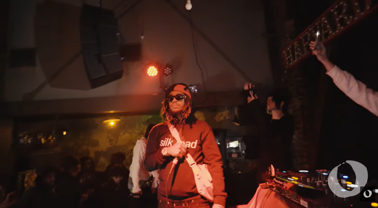 Luci4 performs during a live show, holding a microphone as fans record from the crowd, posted in May 2025 | Source: Youtube/laruesview