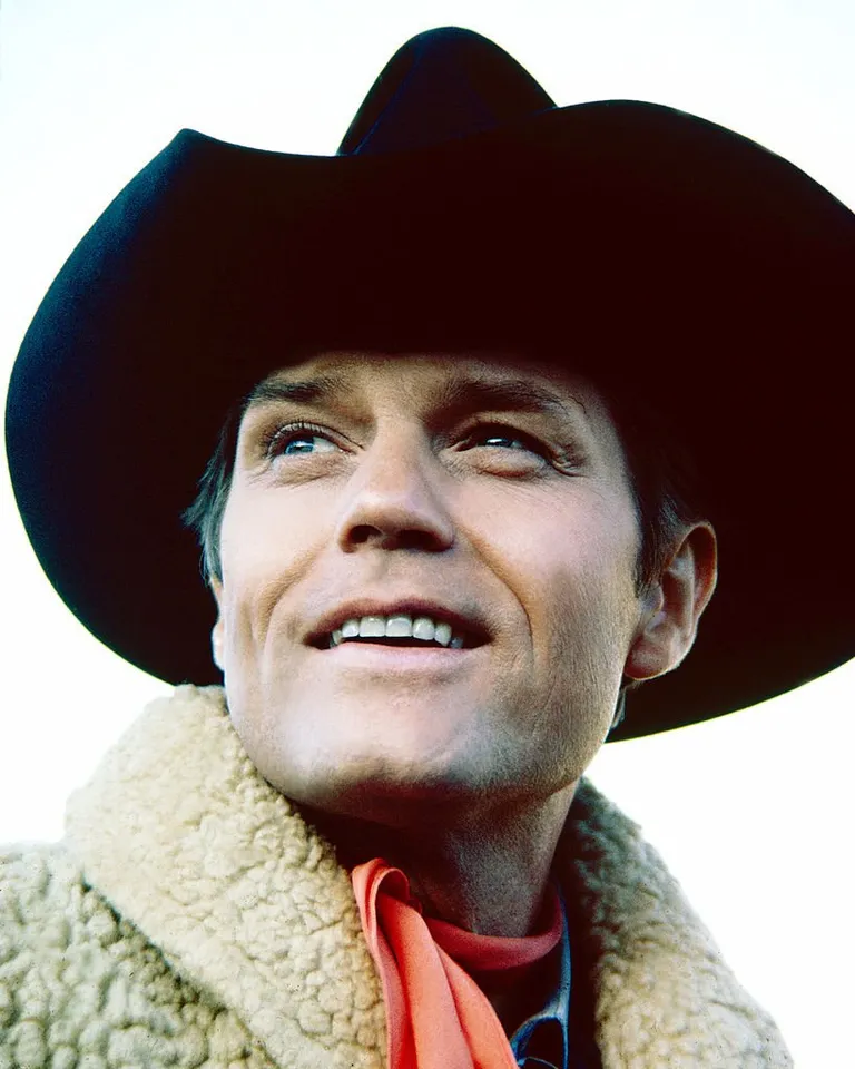 L'acteur américain Jack Lord portant un chapeau de cow-boy noir et une veste polaire blanche avec un foulard rouge, vers 1970. | Photo : Getty Images