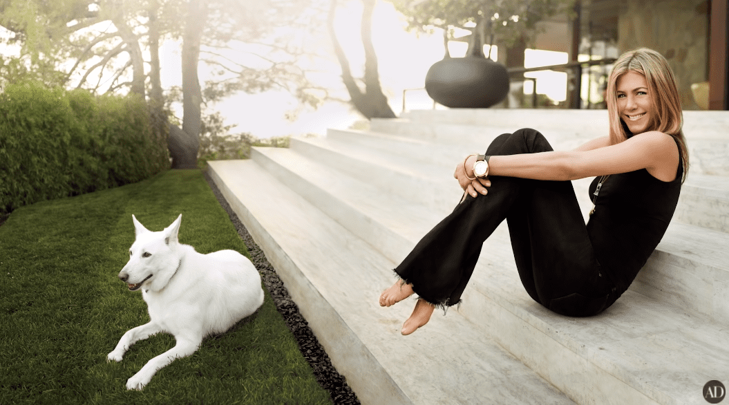 Jennifer Aniston sitting outside her LA home with her dog. | Photo: YouTube/Architectural Digest