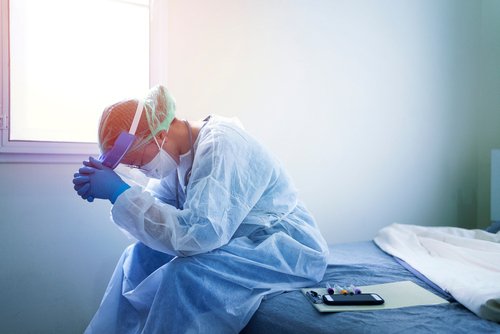 Arzt in steriler Kleidung birgt verzweifelt Gesicht in den Händen | Quelle: Shutterstock