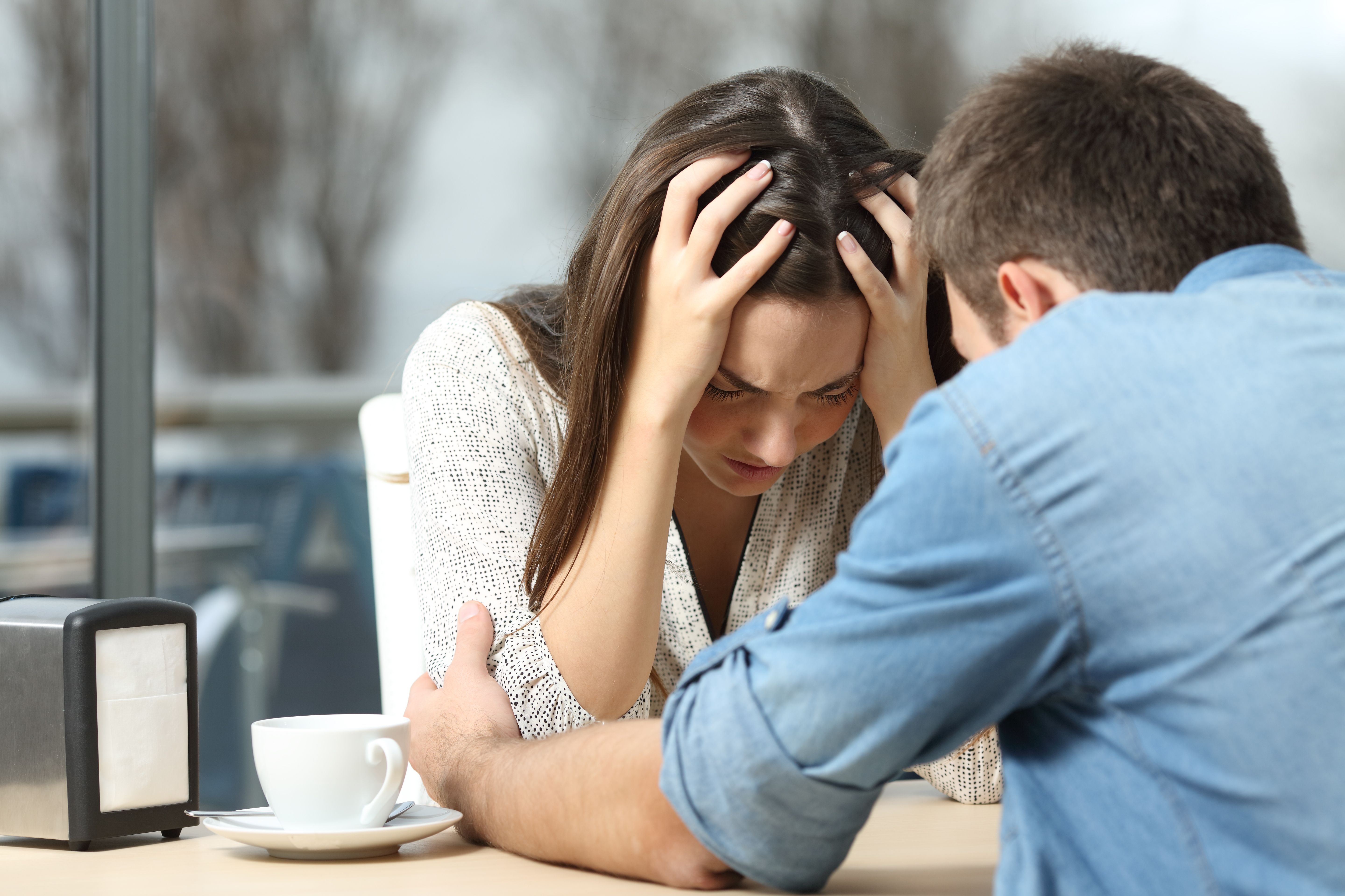 Woman looking stressed with her hands on her head while engaging with a man. | Photo: Shutterstock