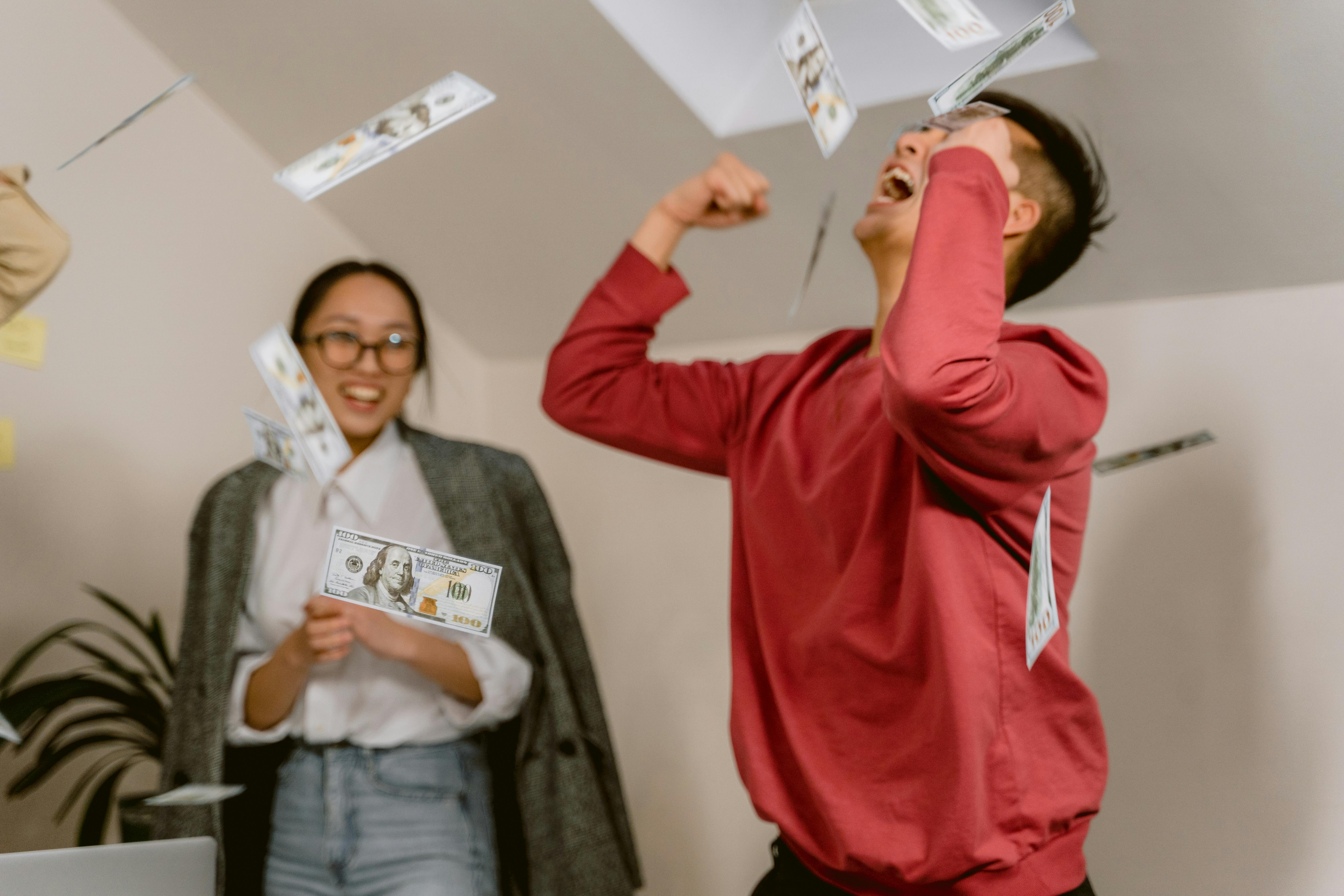 A woman watching a man celebrate by throwing money in the air | Source: Pexels