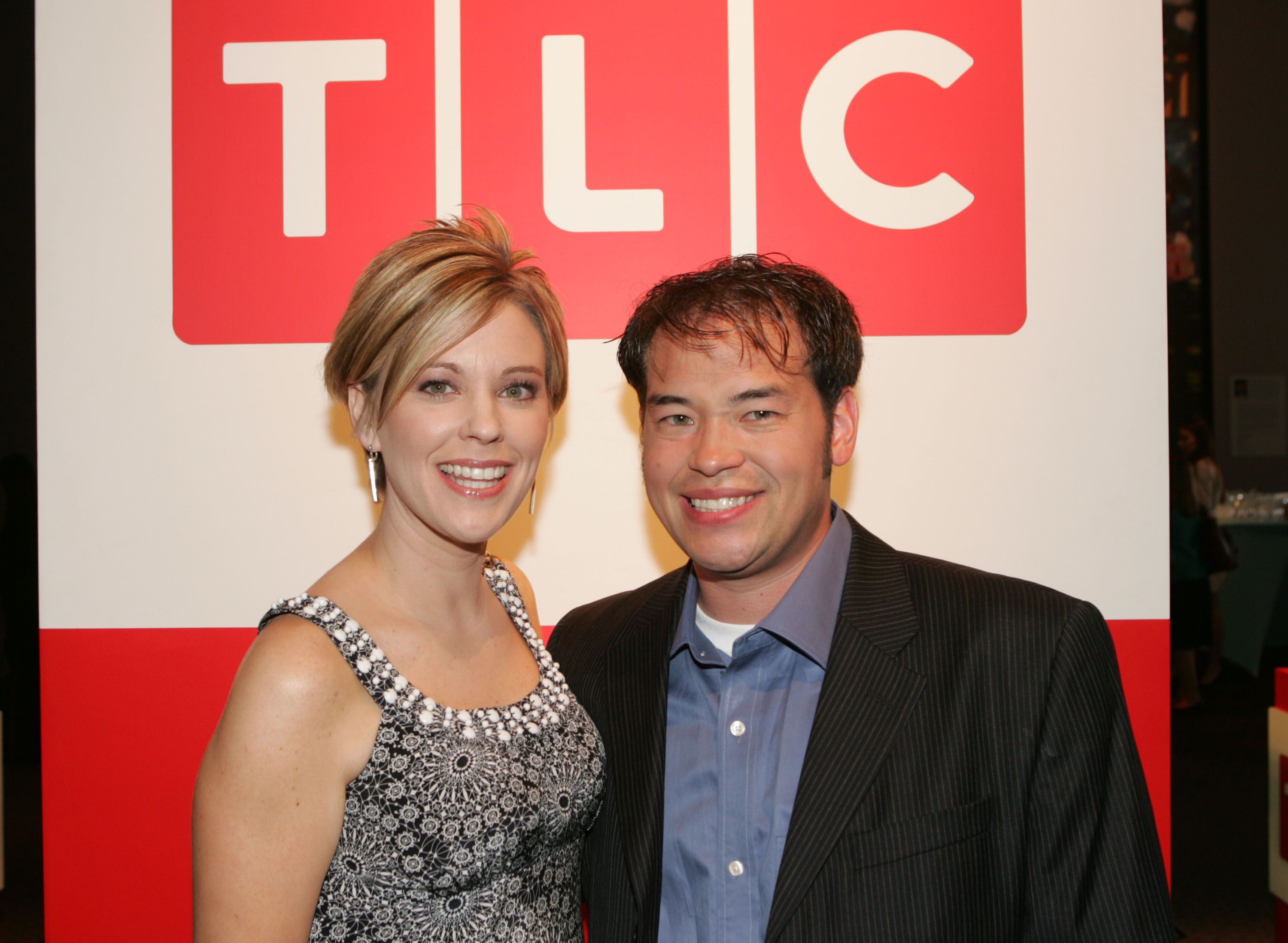 At the Discovery Upfront in New York City, Kate Gosselin wears a black-and-white beaded dress with a square neckline and her signature short layered bob, posing with Jon Gosselin in front of a TLC backdrop during their peak "Jon & Kate Plus 8" fame.