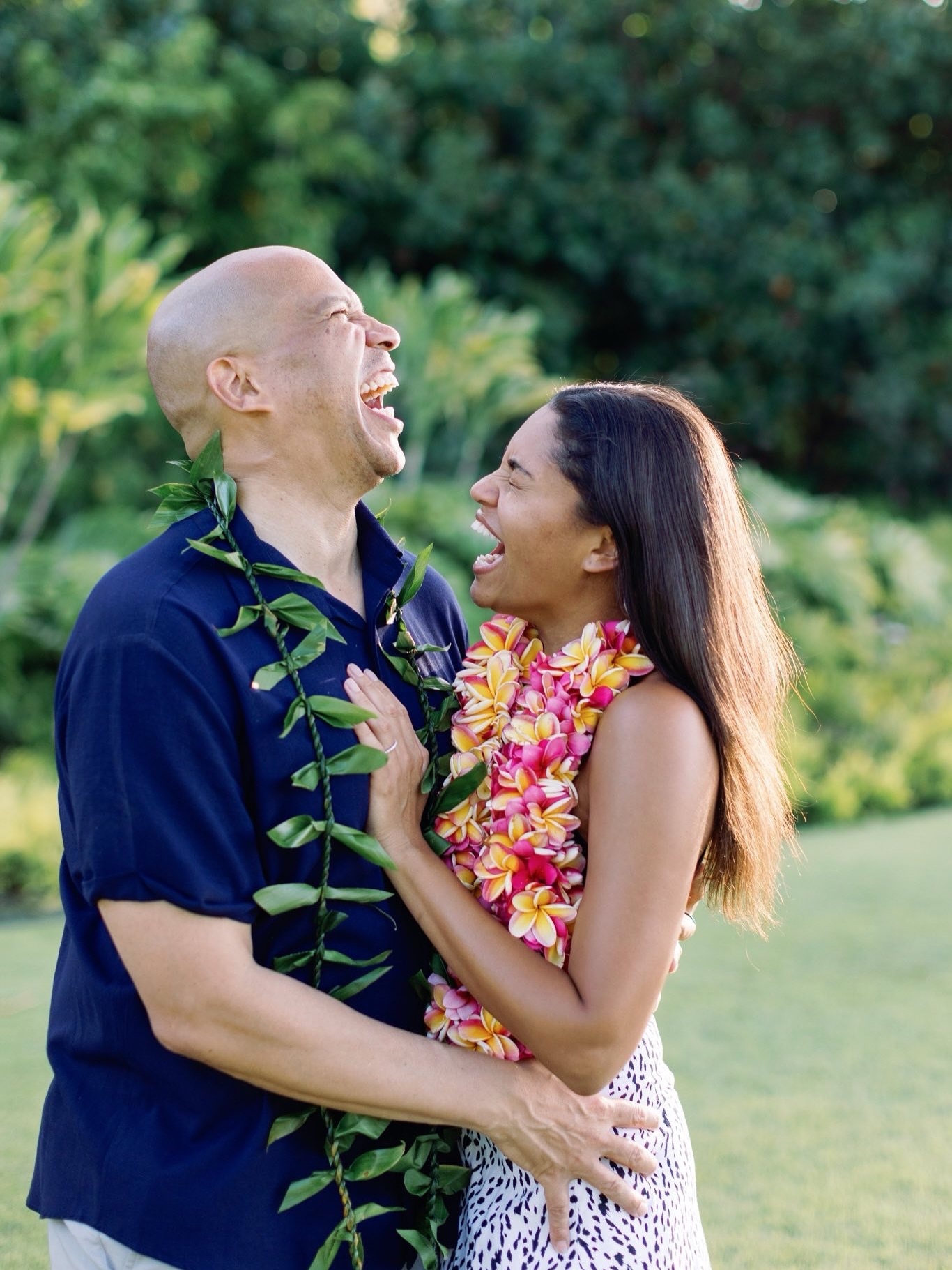 Cory Booker and Alexis Lewis laugh in sync, their expressions mirroring pure happiness as they stand close together, surrounded by lush greenery and glowing with post-proposal bliss. | Source: Instagram/corybooker
