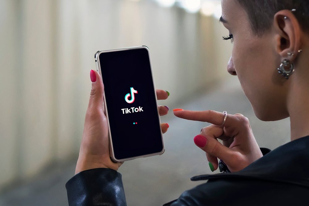 A photo of a lady holding a phone with the logo of Tik Tok on the screen | Photo: Shutterstock