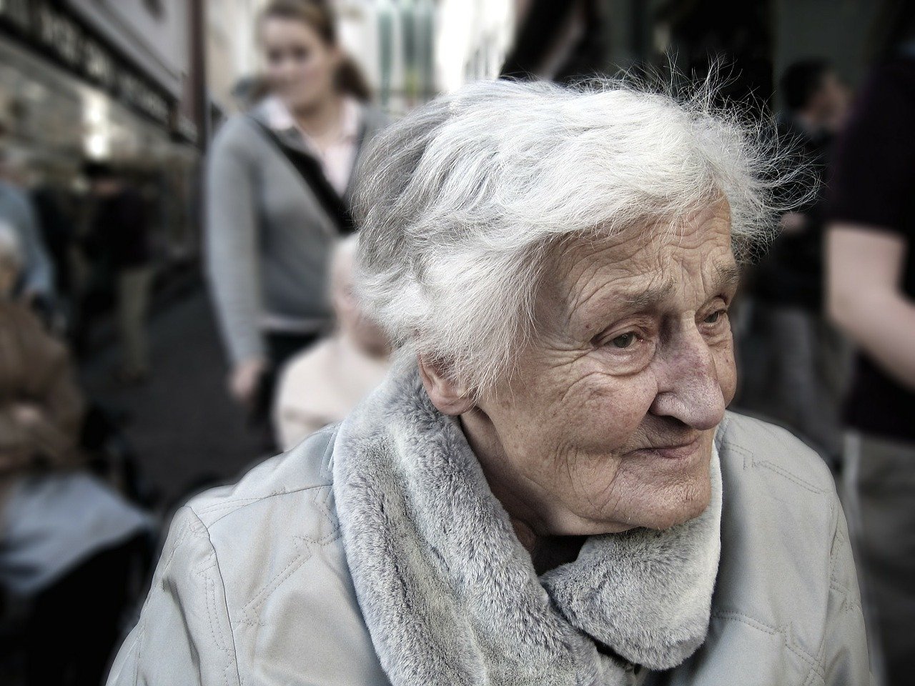 A close-up of an older woman with others behind her. | Photo: Pixabay