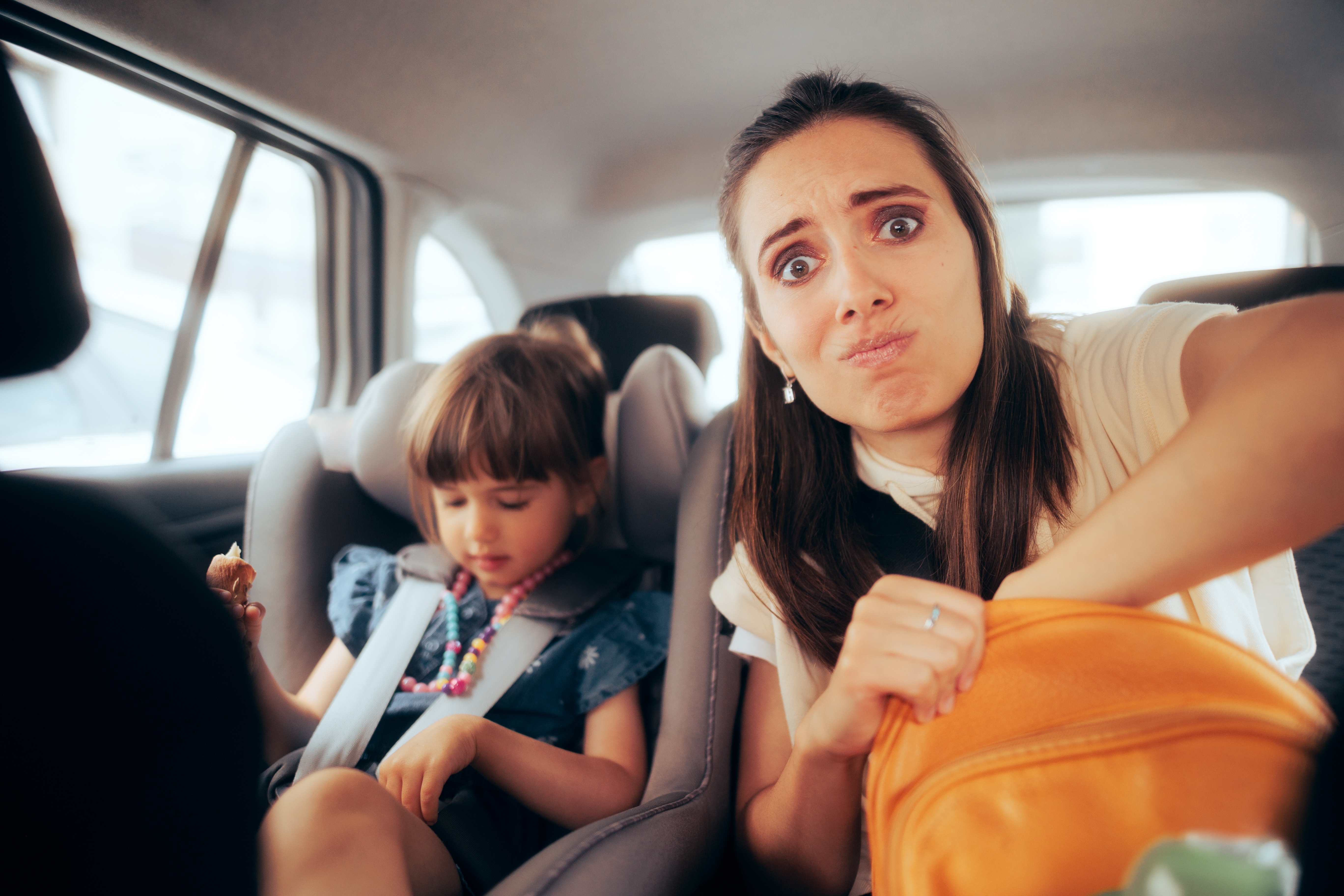 A stressed woman sitting in a car with a little girl | Source: Shutterstock