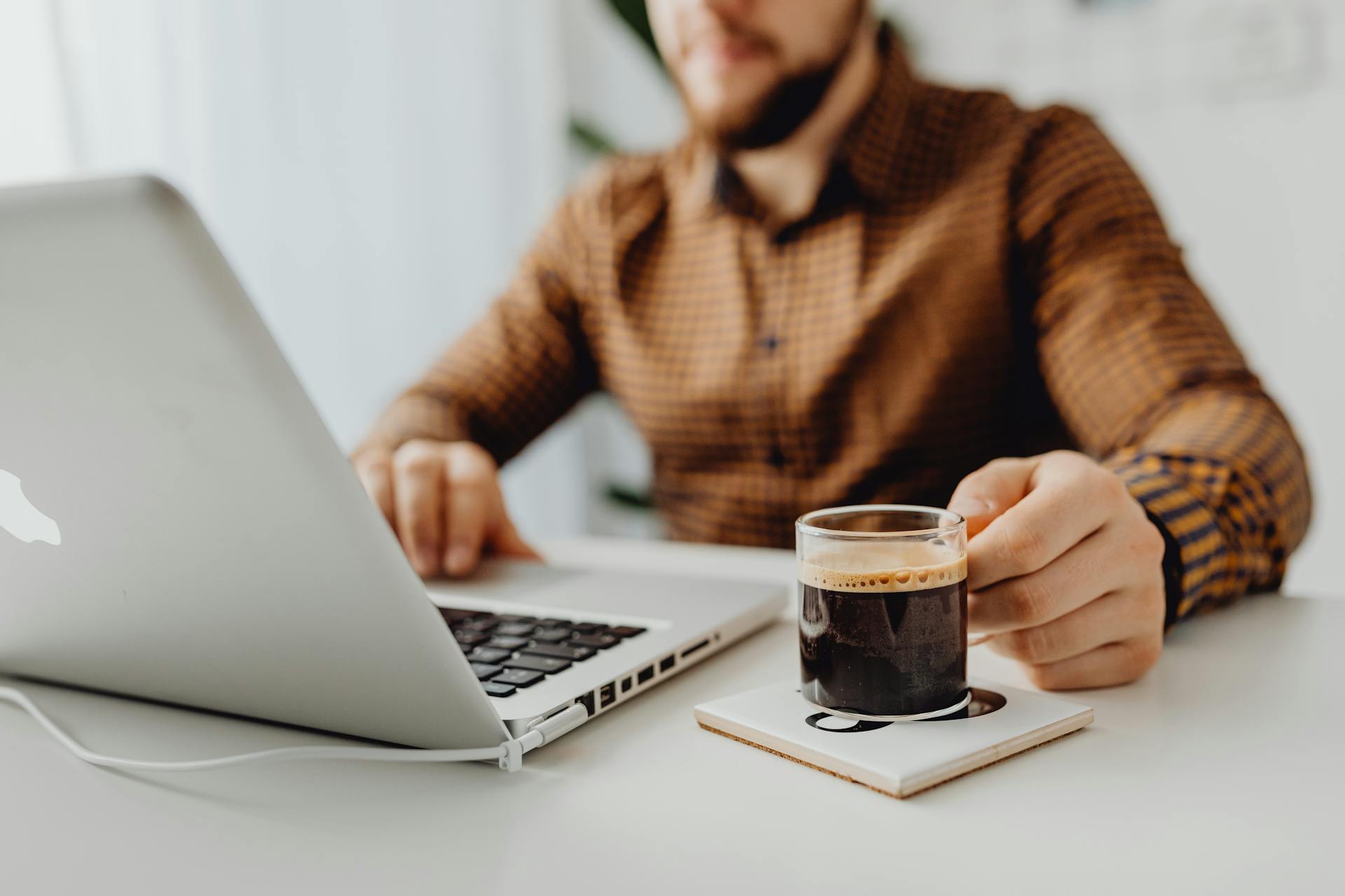 A man drinking coffee and working on his laptop | Source: Pexels