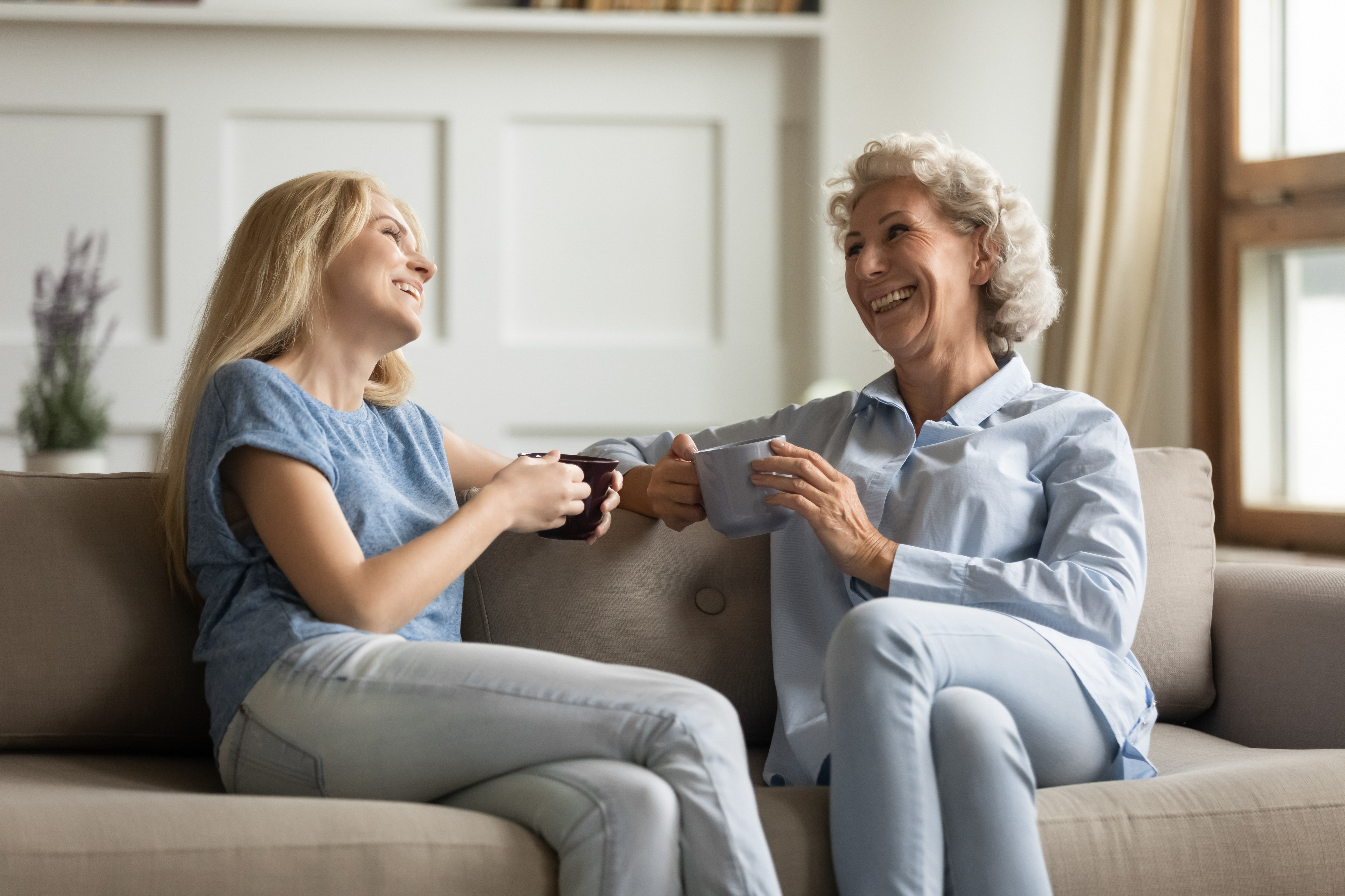 A younger and older woman bonding on a couch | Source: Shutterstock