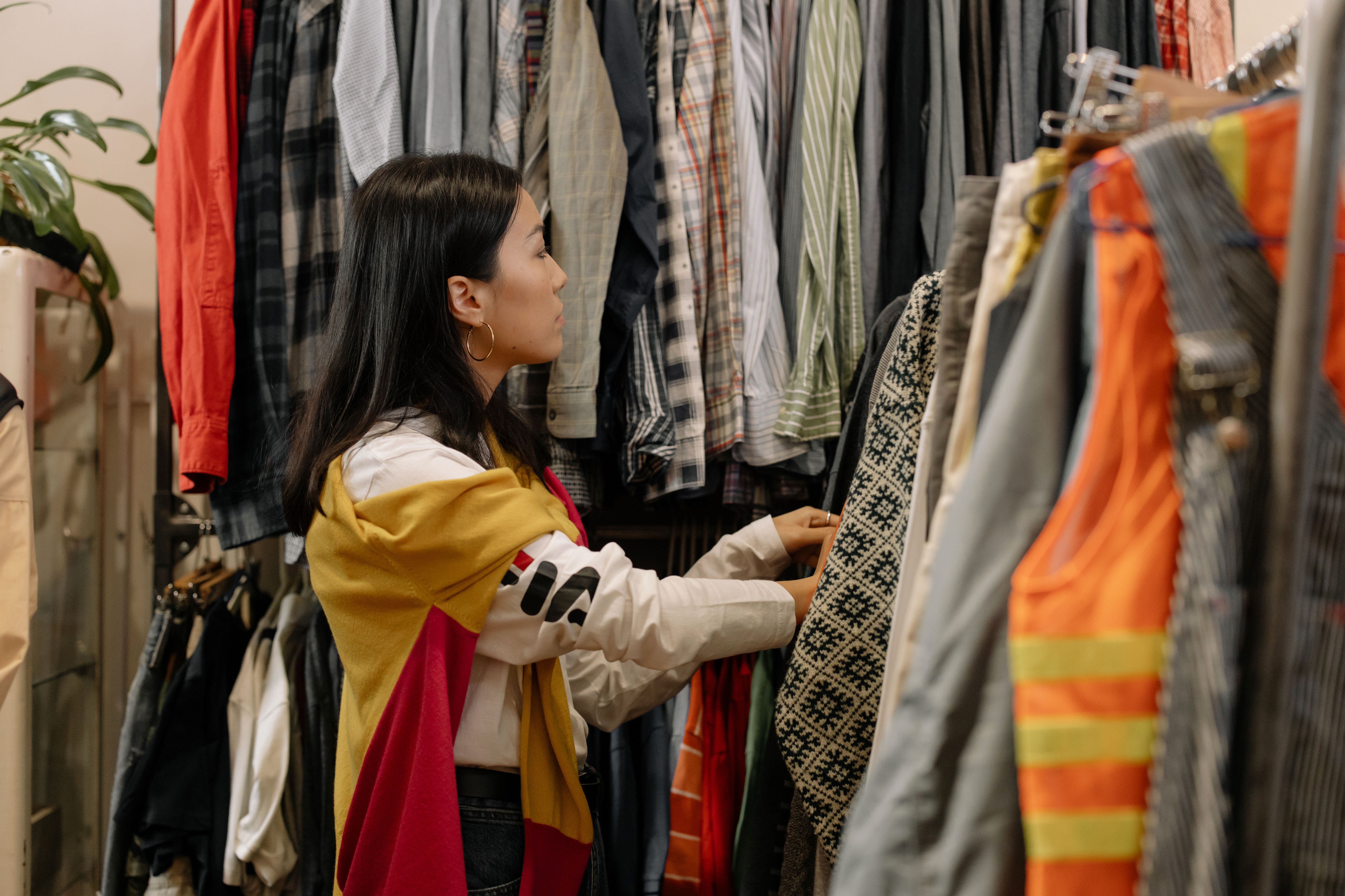 A woman looks through a rack of clothes while shopping. | Source: Pexels