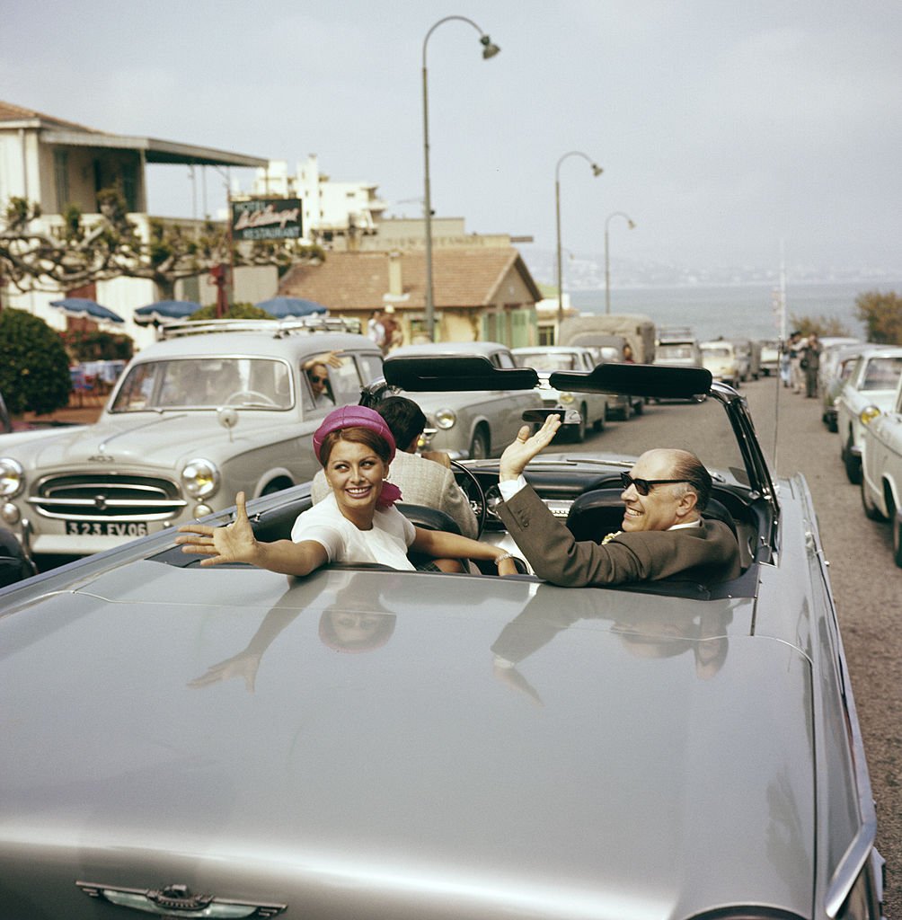 Seven-time Golden Globe Award winner Sophia Loren in a car with her husband, Carlo Ponti waving at the crowd in 1960. | Photo: Getty Images