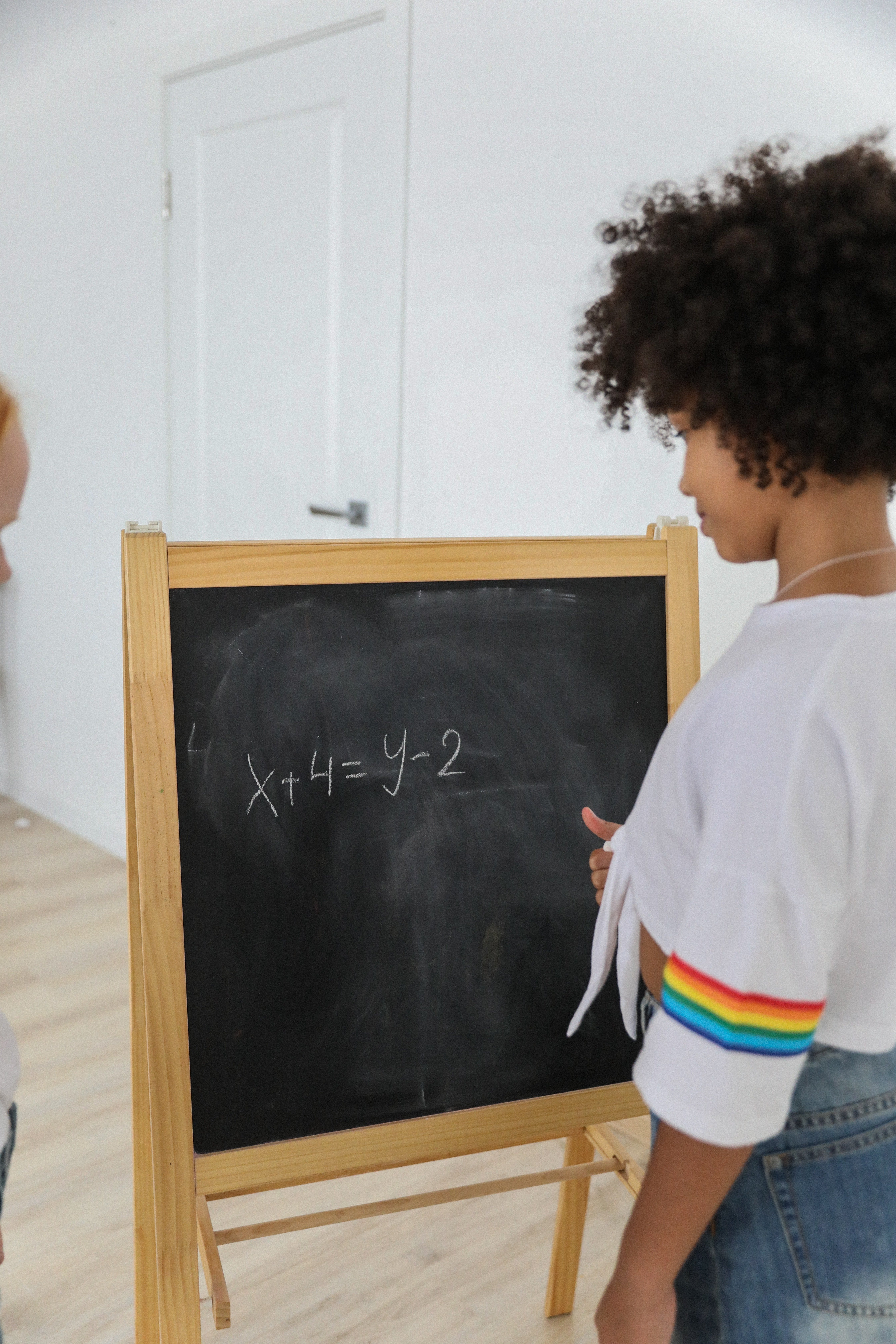A girl attempts to figure out the equation on the chalkboard in front of her | Photo: Pexels