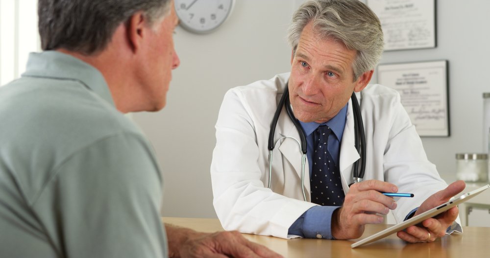 A doctor talking with a patient in the office. | Photo: Shutterstock