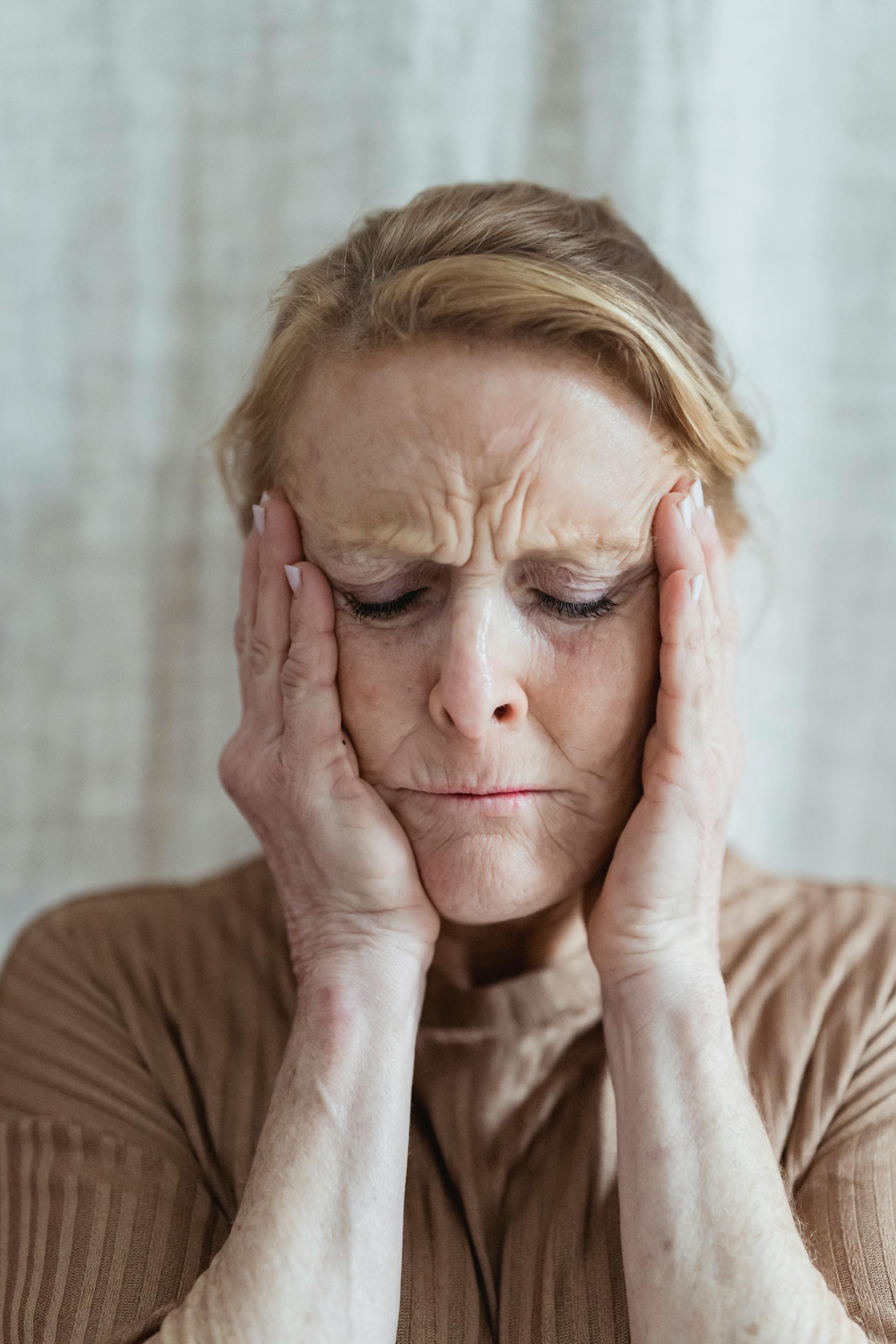 A stressed senior woman holding her face | Source: Pexels