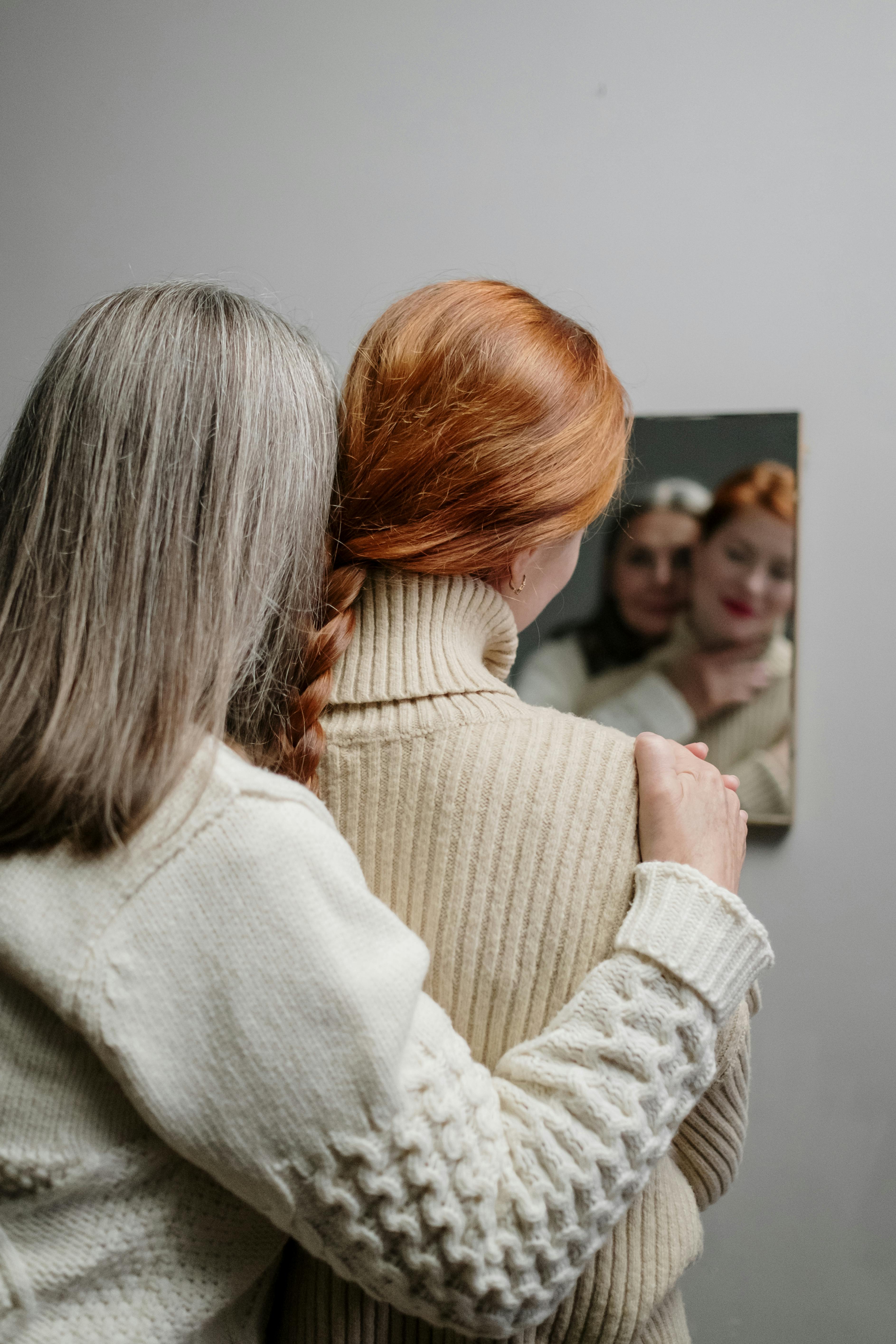 An older woman embracing a younger one while looking in the mirror | Source: Pexels