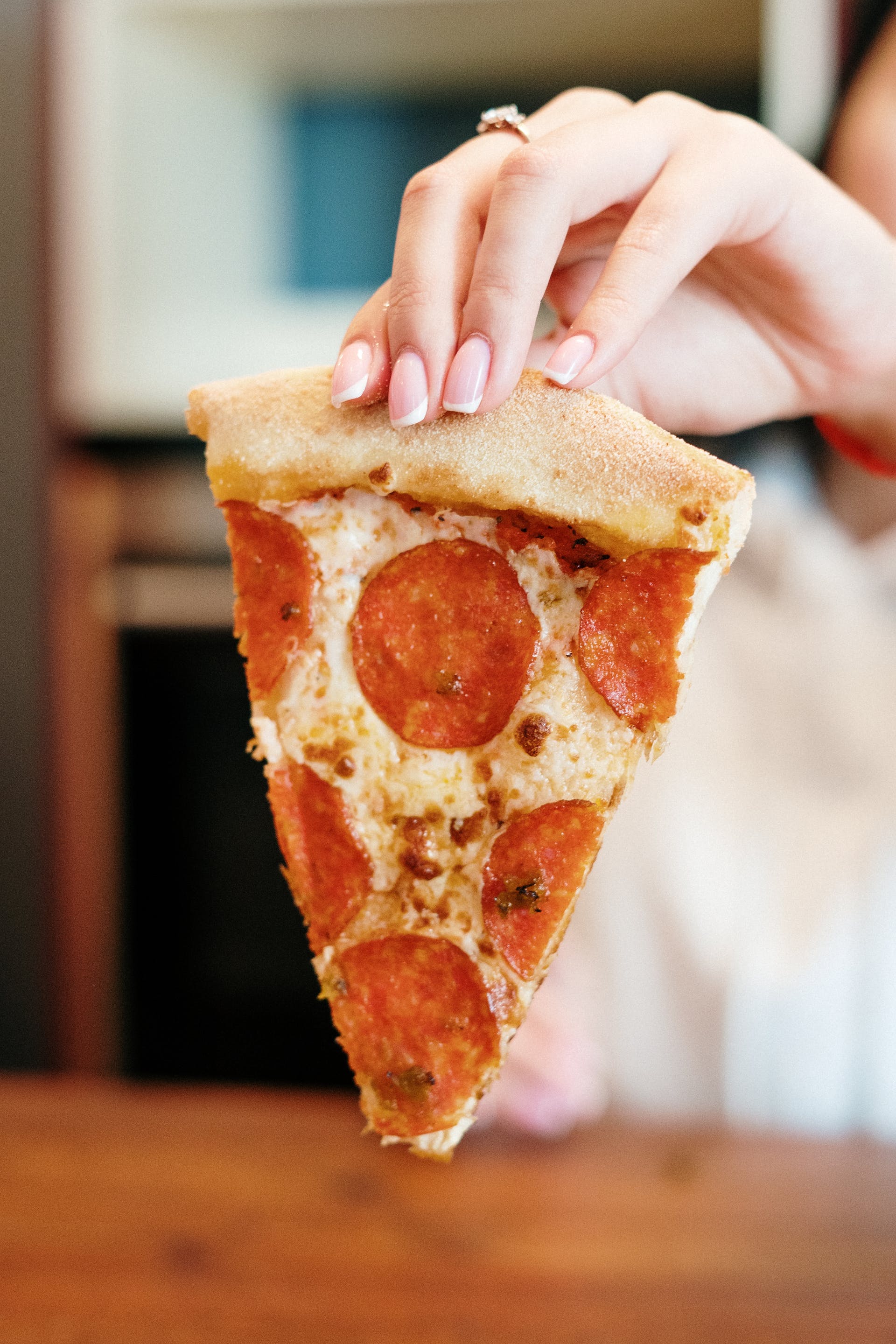 A woman holding a slice of pizza | Source: Pexels