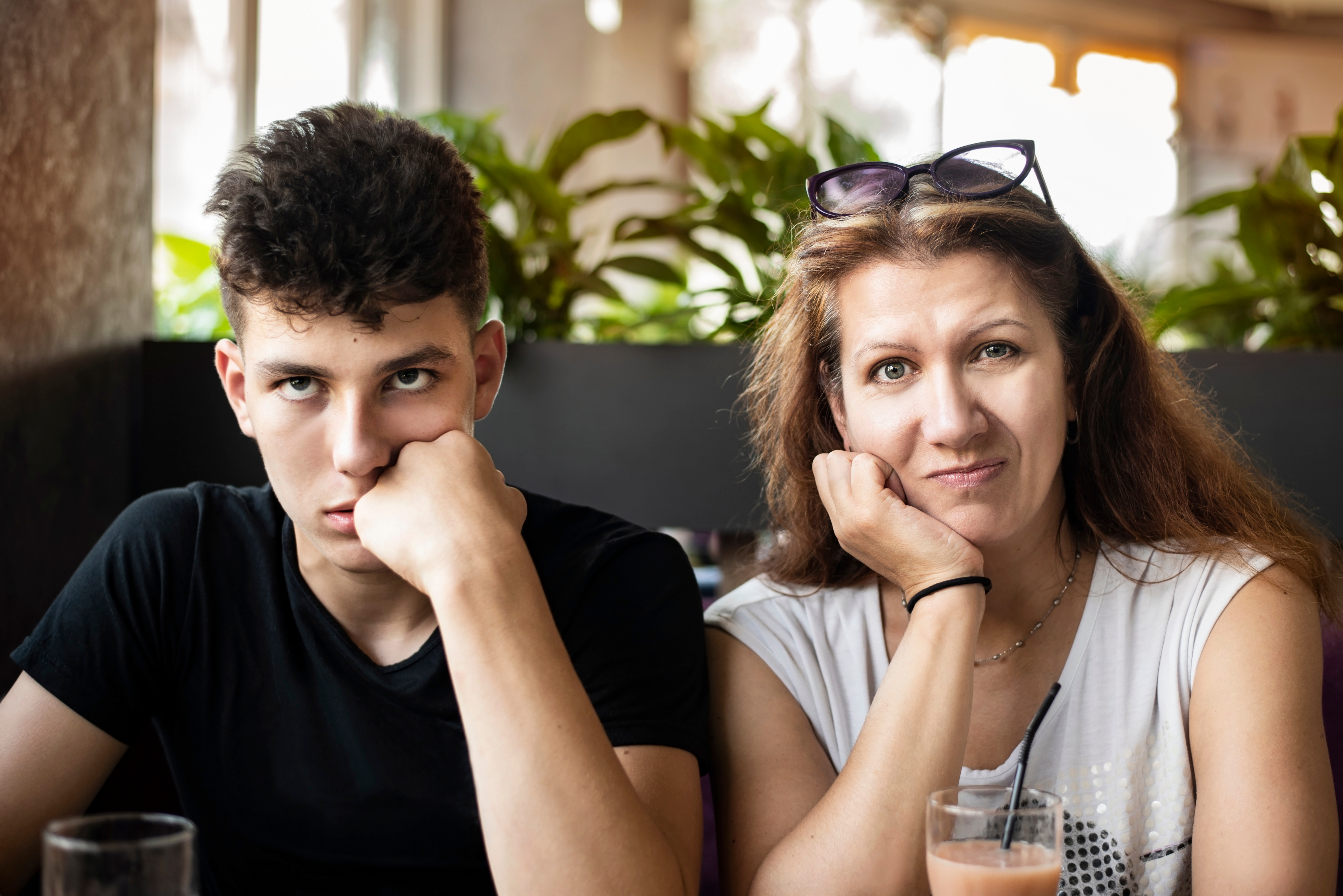 Frustrated teenage boy sitting next to a woman with a confused expression | Source: Shutterstock