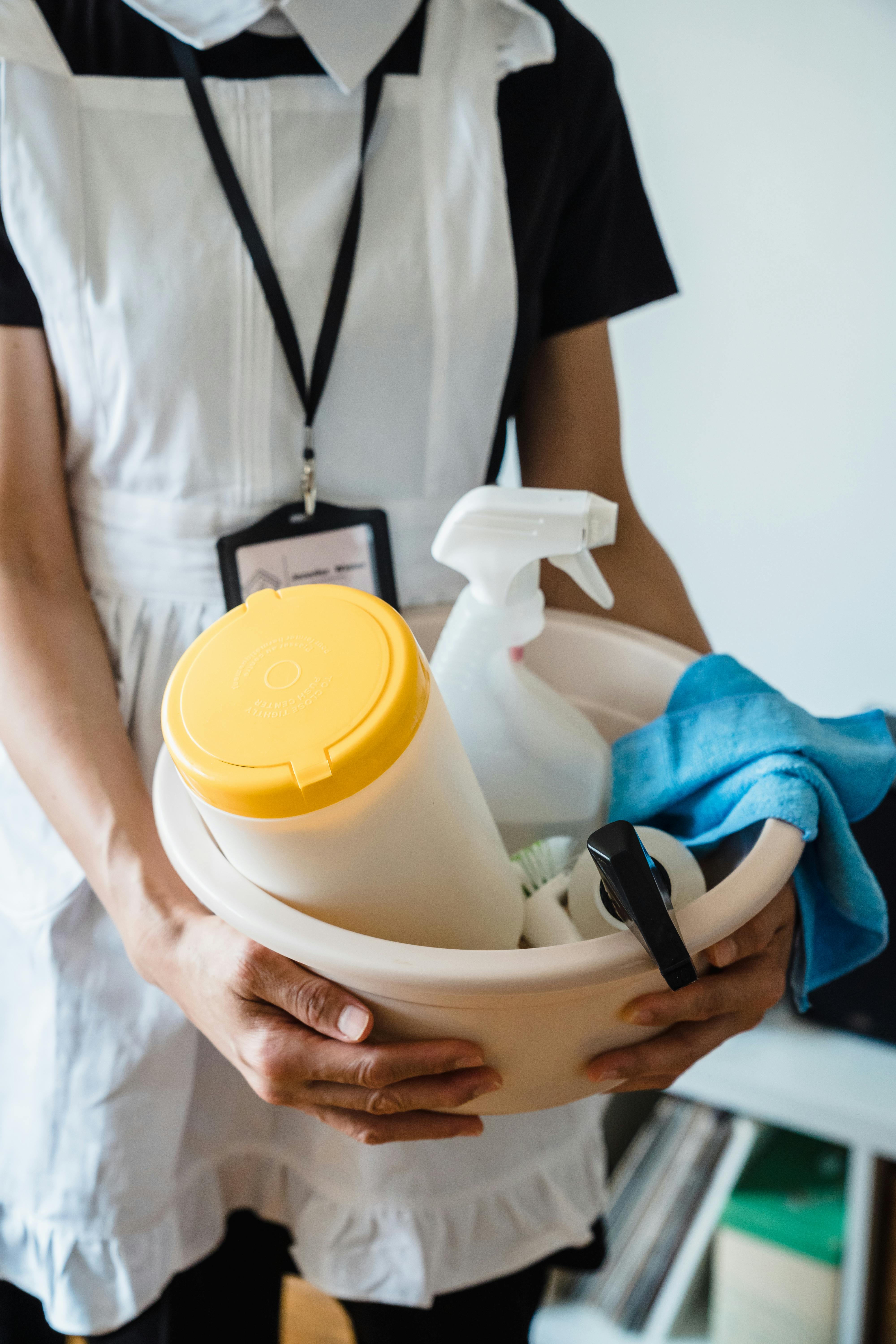 Mujer sosteniendo un lavabo de plástico con materiales de limpieza | Fuente: Pexels