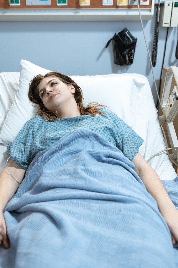 Una mujer acostada en una cama de hospital, sonrie. | Foto: Pexels