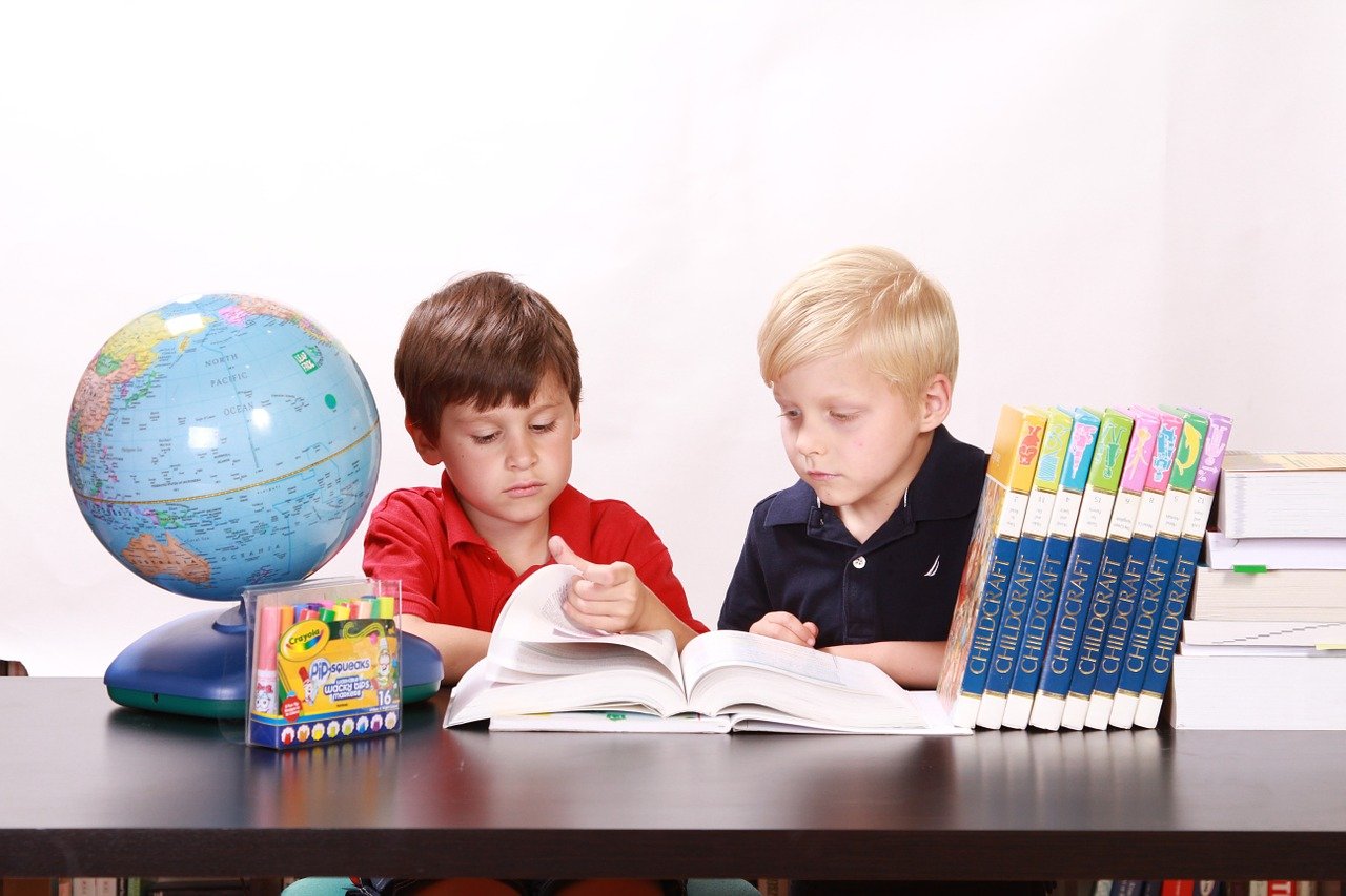 A photo of two young boys reading a book. | Photo: Pixabay