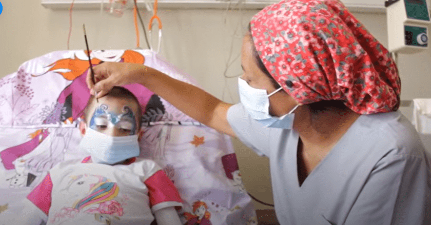 Enfermera pintando a una niña.│ Foto: Captura de Facebook/Hospital Garrahan