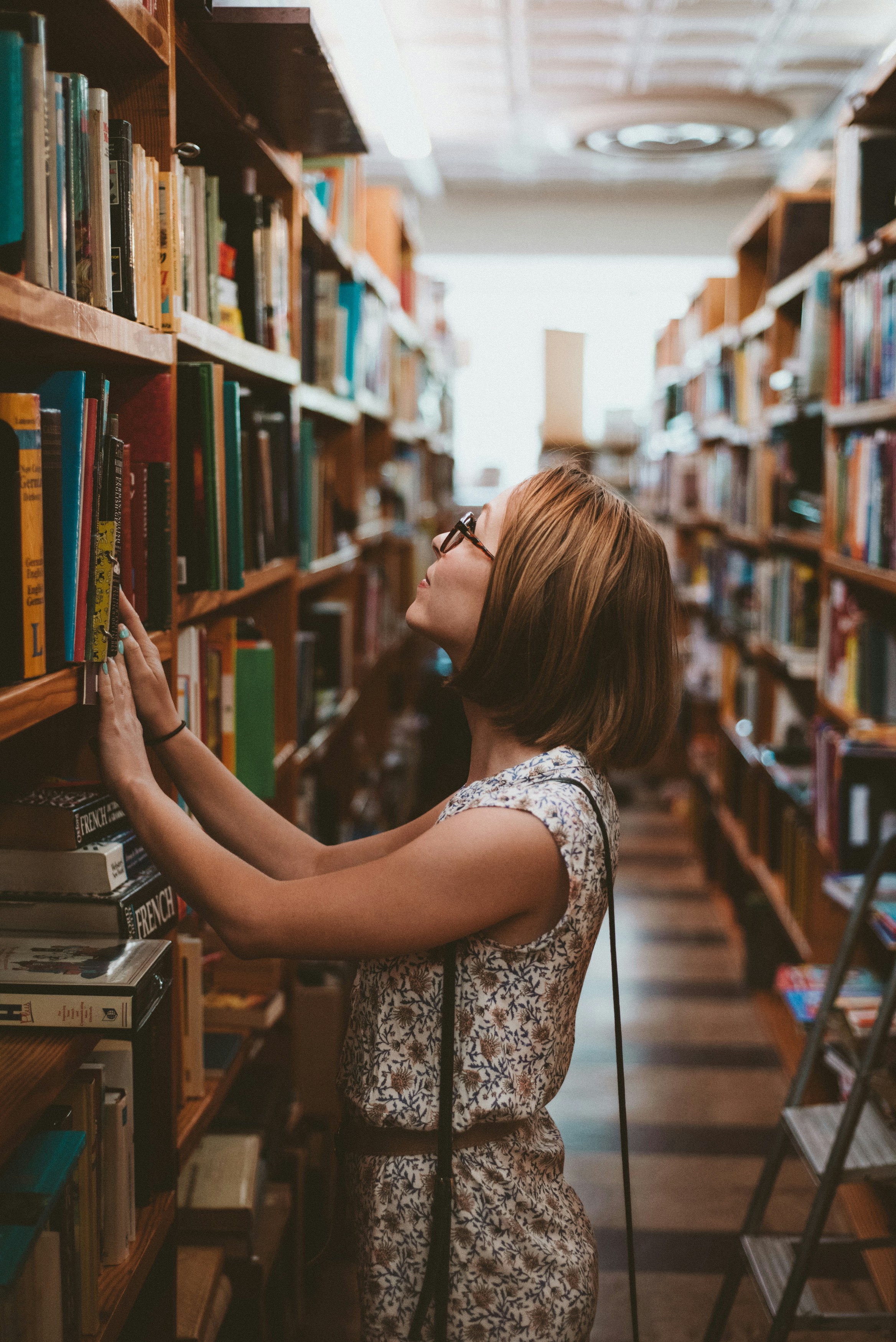 A woman reaching for a book in a library | Source: Unsplash