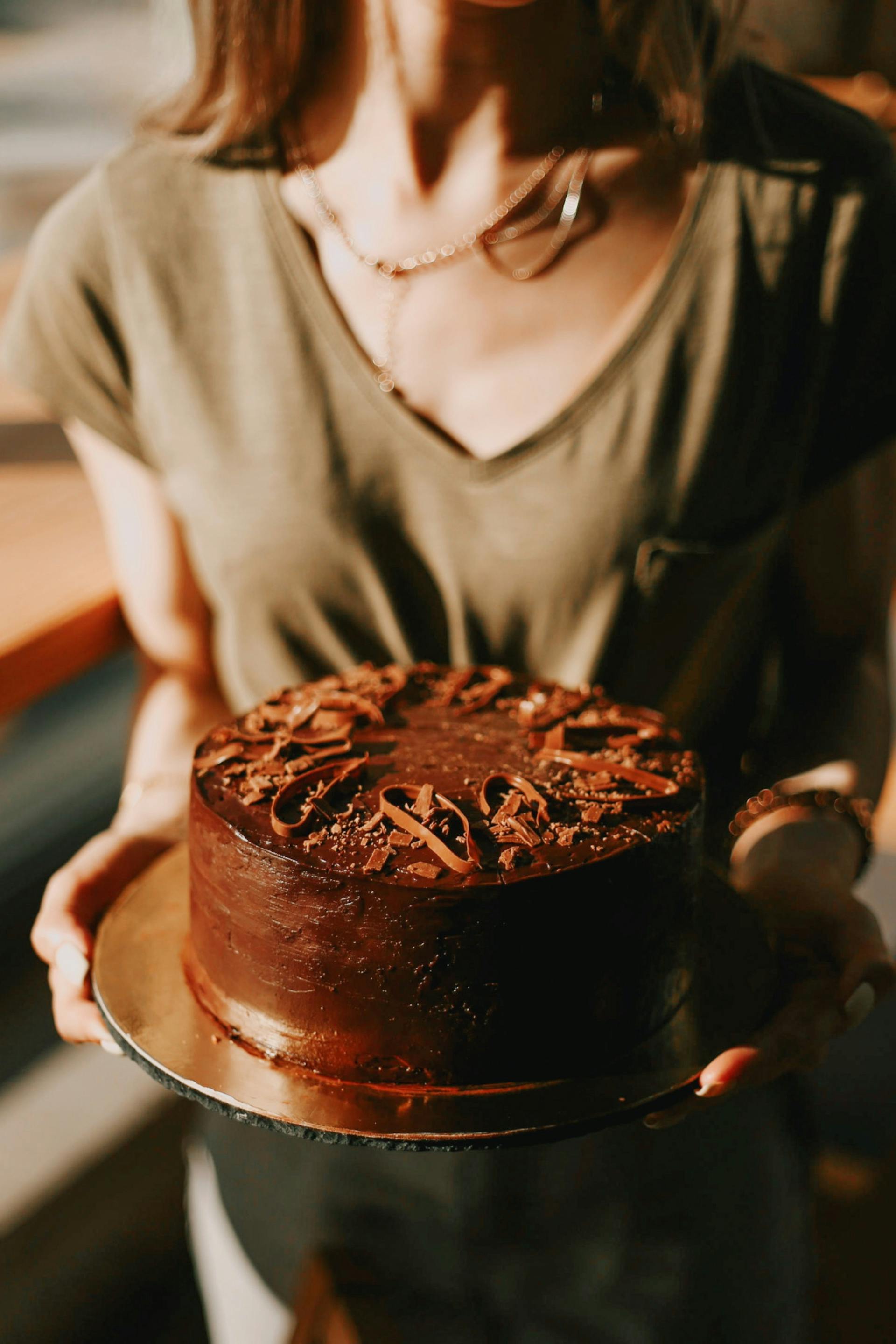 A closeup of a woman holding a chocolate cake | Source: Pexels