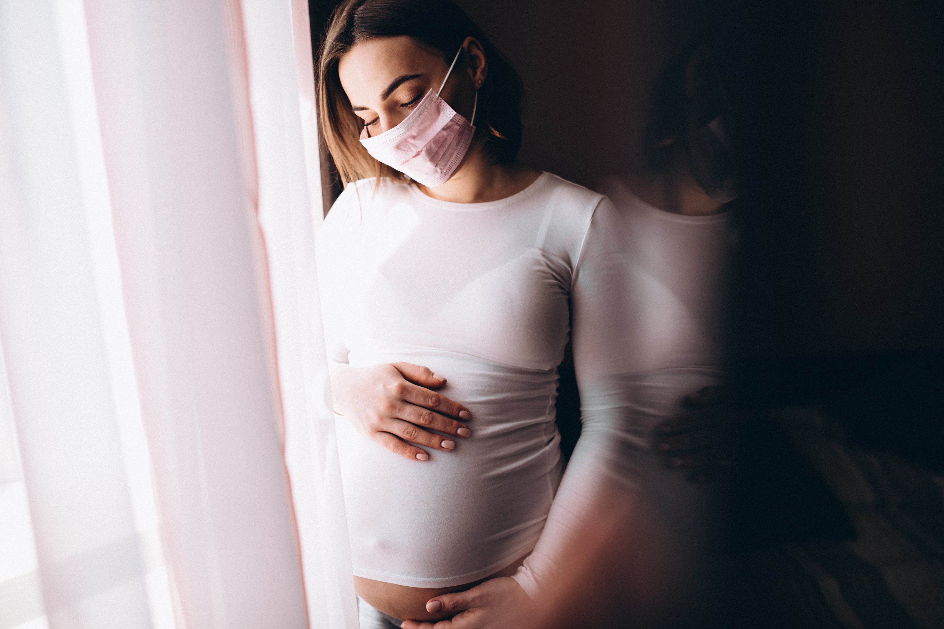 Une femme enceinte portant un masque médical. | Photo : Getty Images