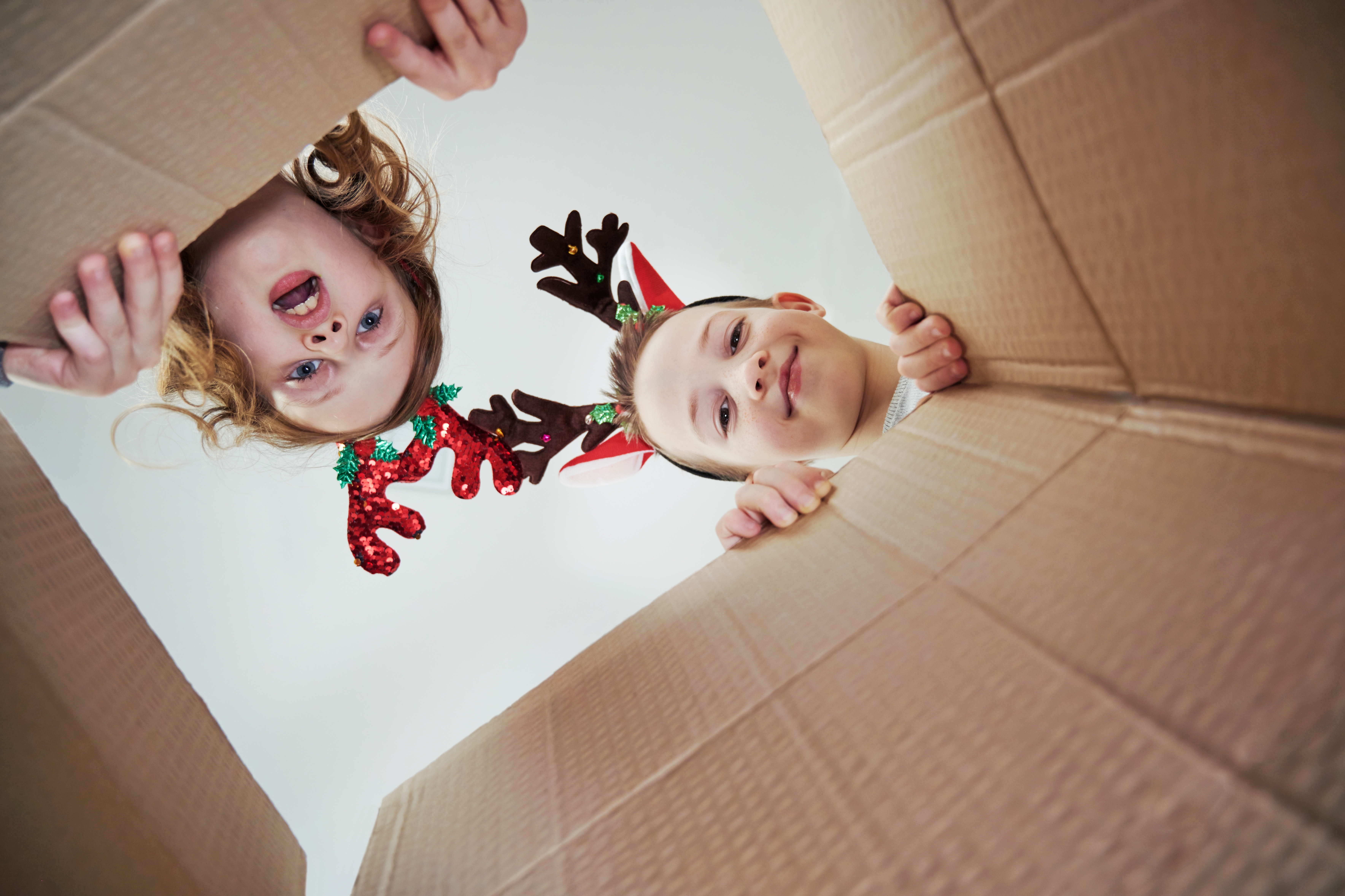 A boy and a girl looking inside a cardboard box | Source: Shutterstock