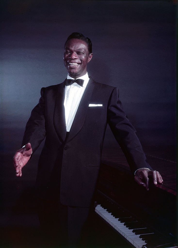 Portrait of American pop and jazz vocalist/pianist Nat King Cole dressed in formal wear, as he poses in front of a piano, 1954 | Photo: Getty Images.