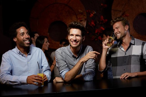 Photo of a cheerful male friends enjoying while having drinks in nightclub | Photo: Getty Images