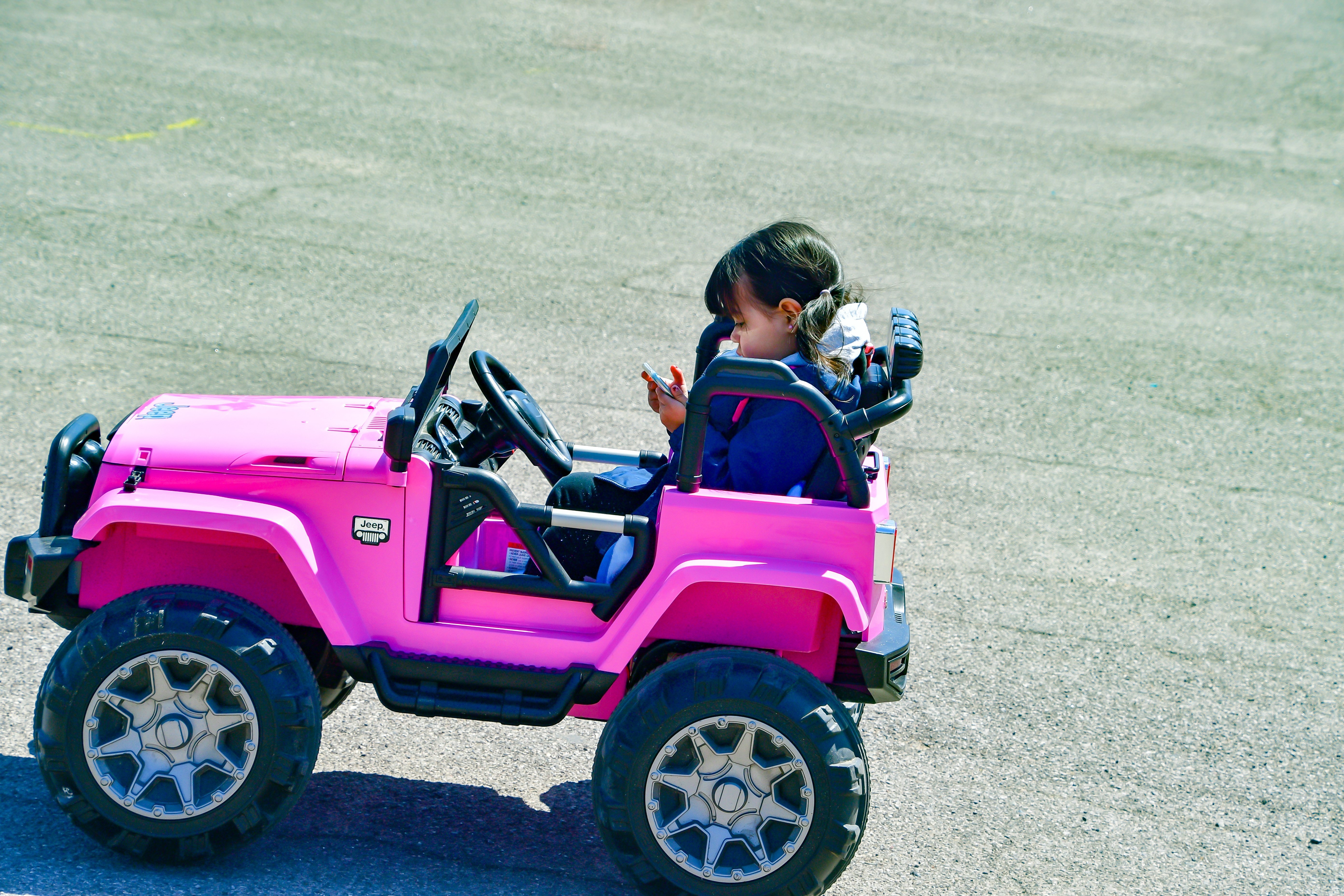 A little girl texting in her toy car. | Source: Shutterstock