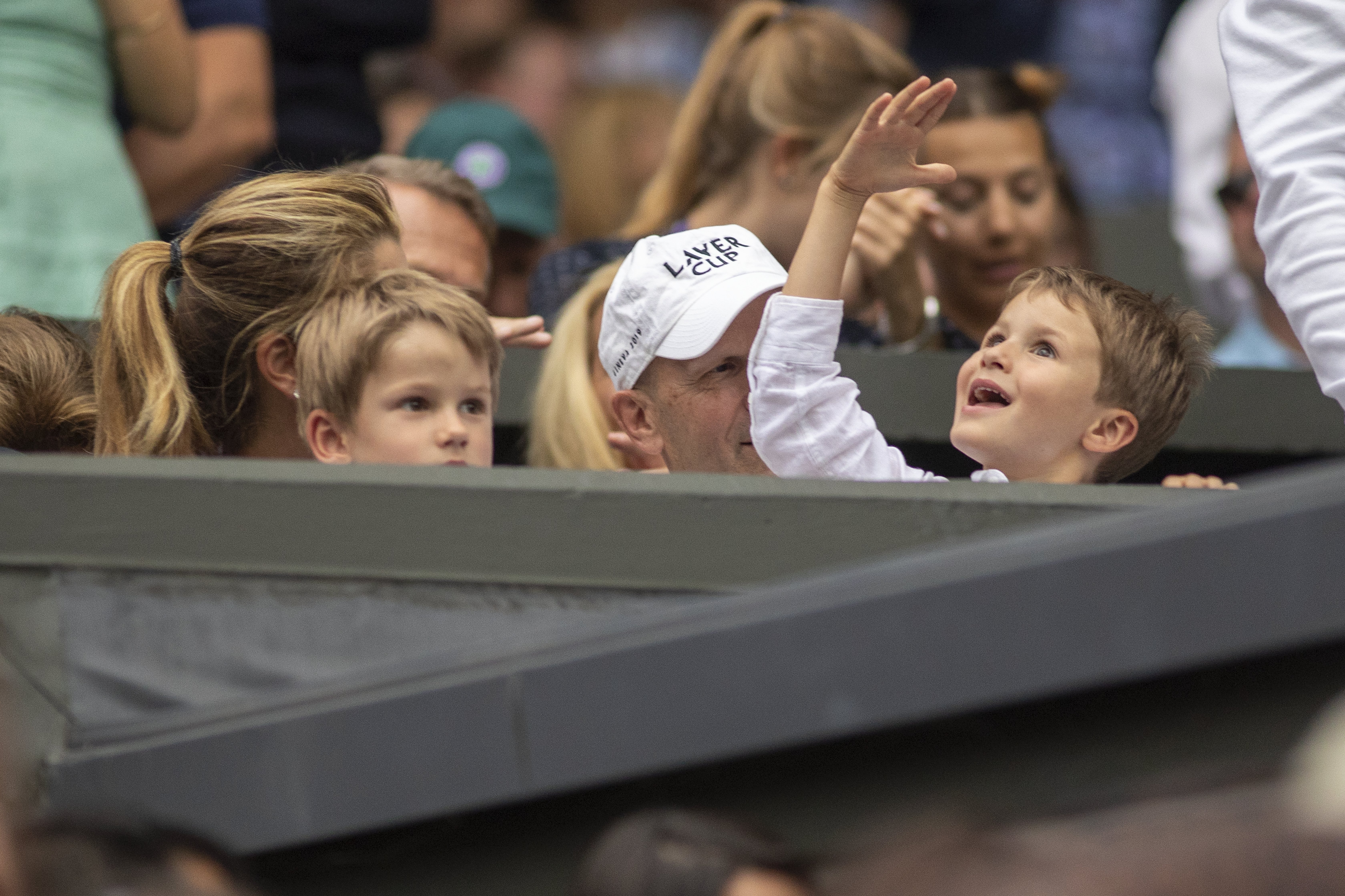 Lennert "Lenny" Federer raises his right hand beside his brother Leo during their father Roger Federer's match against Matteo Berrettini of Italy at Wimbledon on July 8, 2019, in London, England. | Source: Getty Images