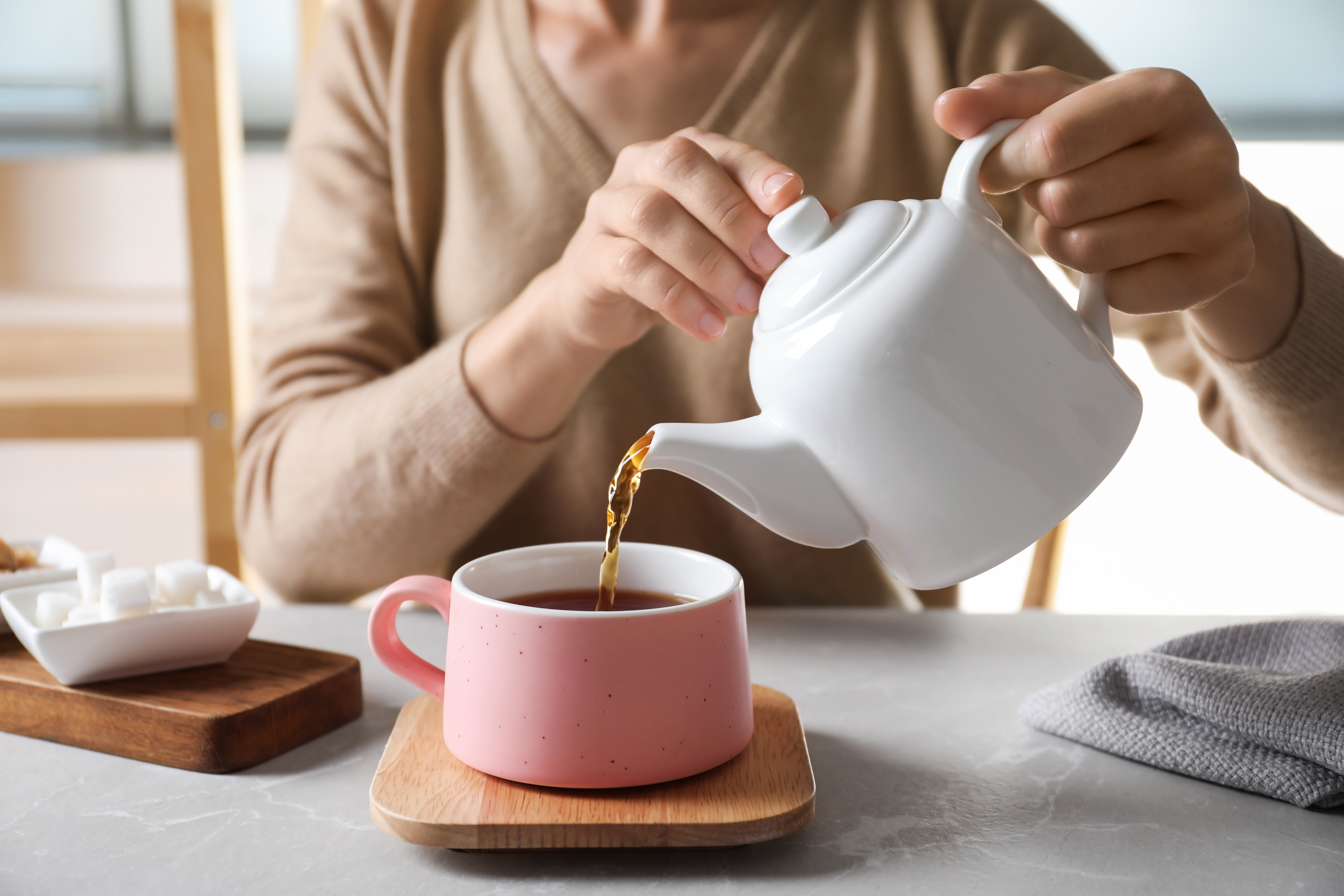 Woman pouring tea into ceramic cup | Source: Shutterstock