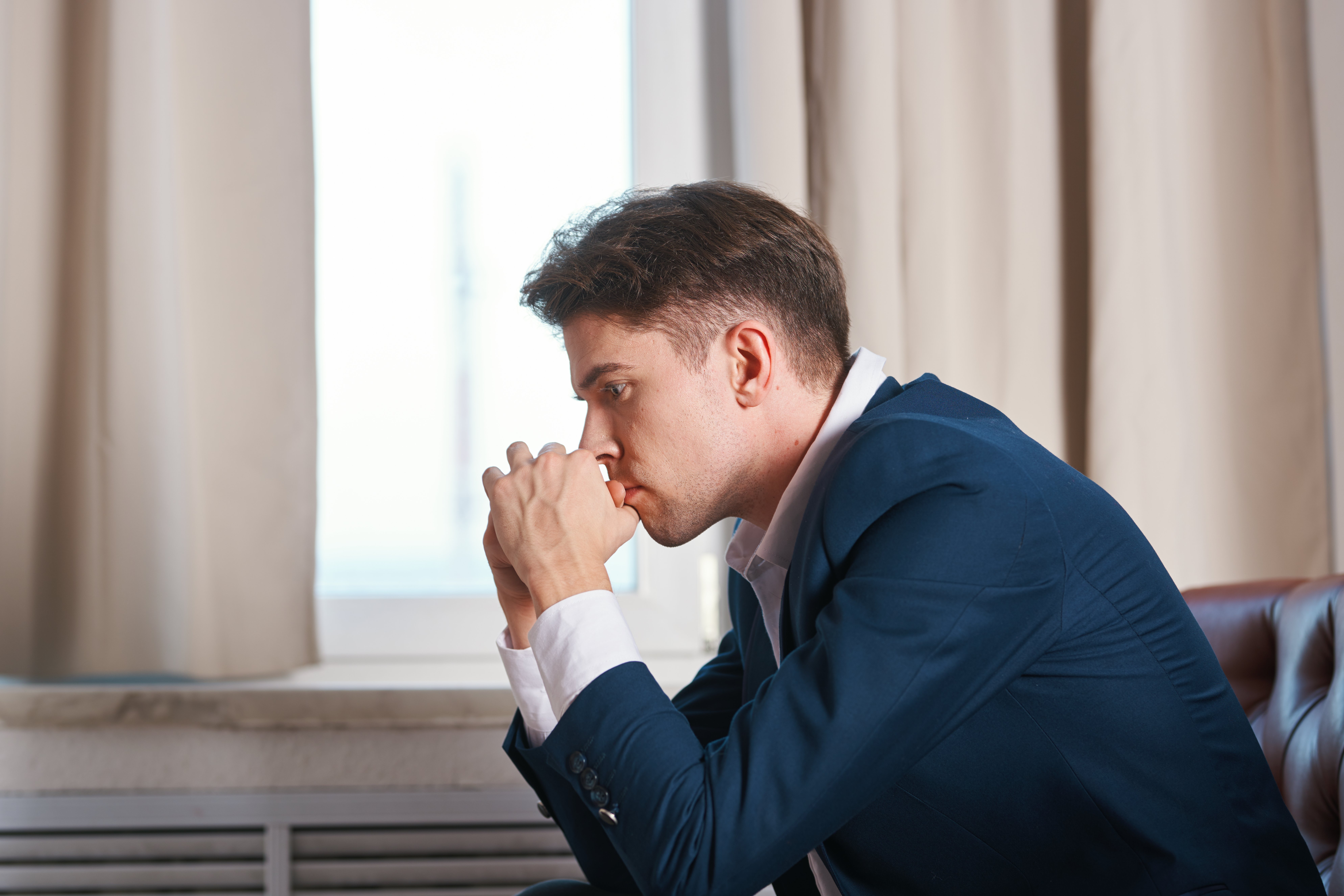 A business man holds his hands near the face with a pensive look of depression melancholy | Photo: Shutterstock.com