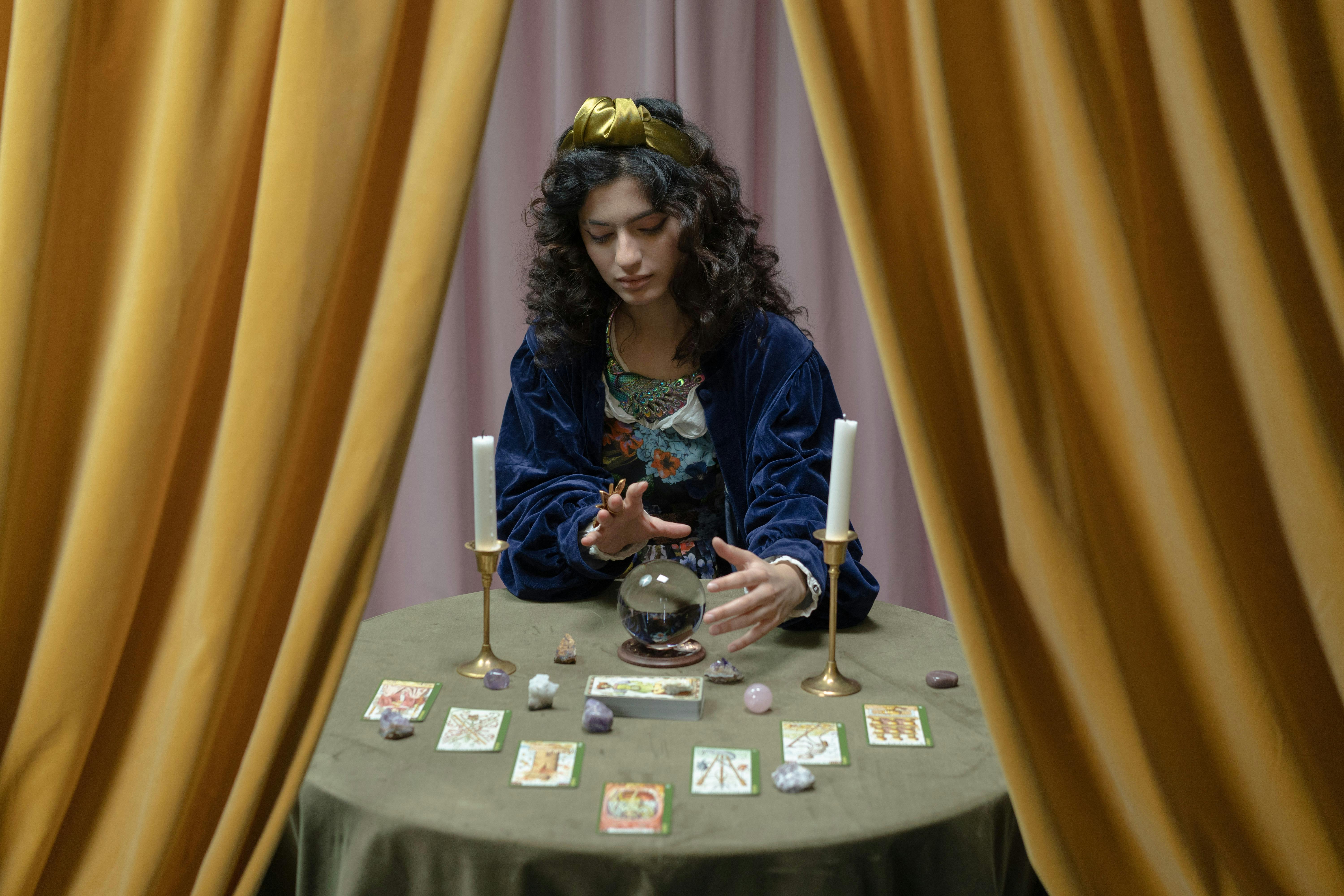 A fortune teller sitting in front of her crystal ball and tarot cards | Source: Pexels