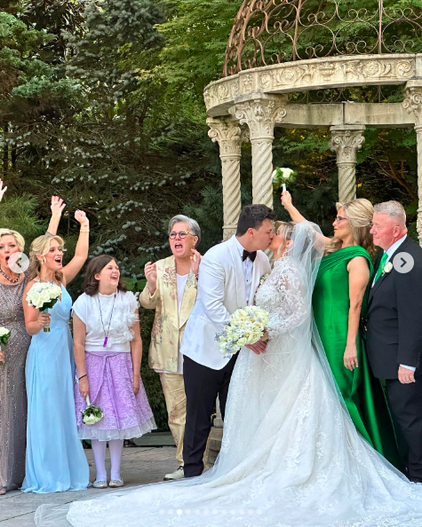 Blake and Teresa O'Donnell sharing a kiss on their wedding day alongside Rosie O'Donnell, Kelli Carpenter and other loved ones, posted on August 18, 2024 | Source: Instagram/rosie