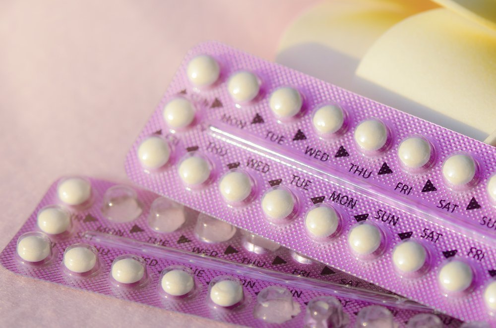 Contraceptif oral avec fleurs de frangipanier sur tissu frise rose | Photo: Shutterstock
