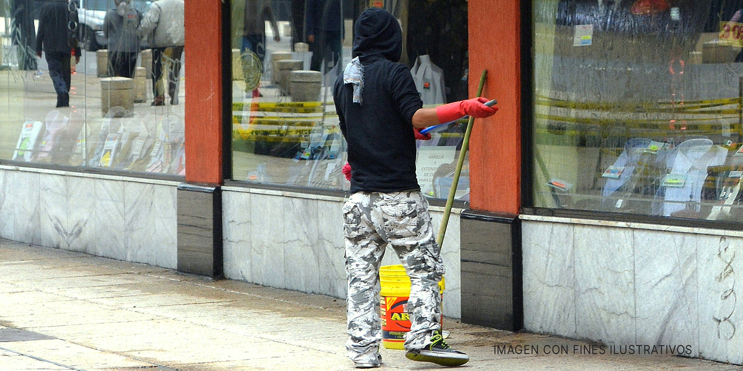 Hombre barriendo el pavimento fuera de una tienda. | Foto: flickr.com/Carl Campbell (CC BY-SA 2.0)