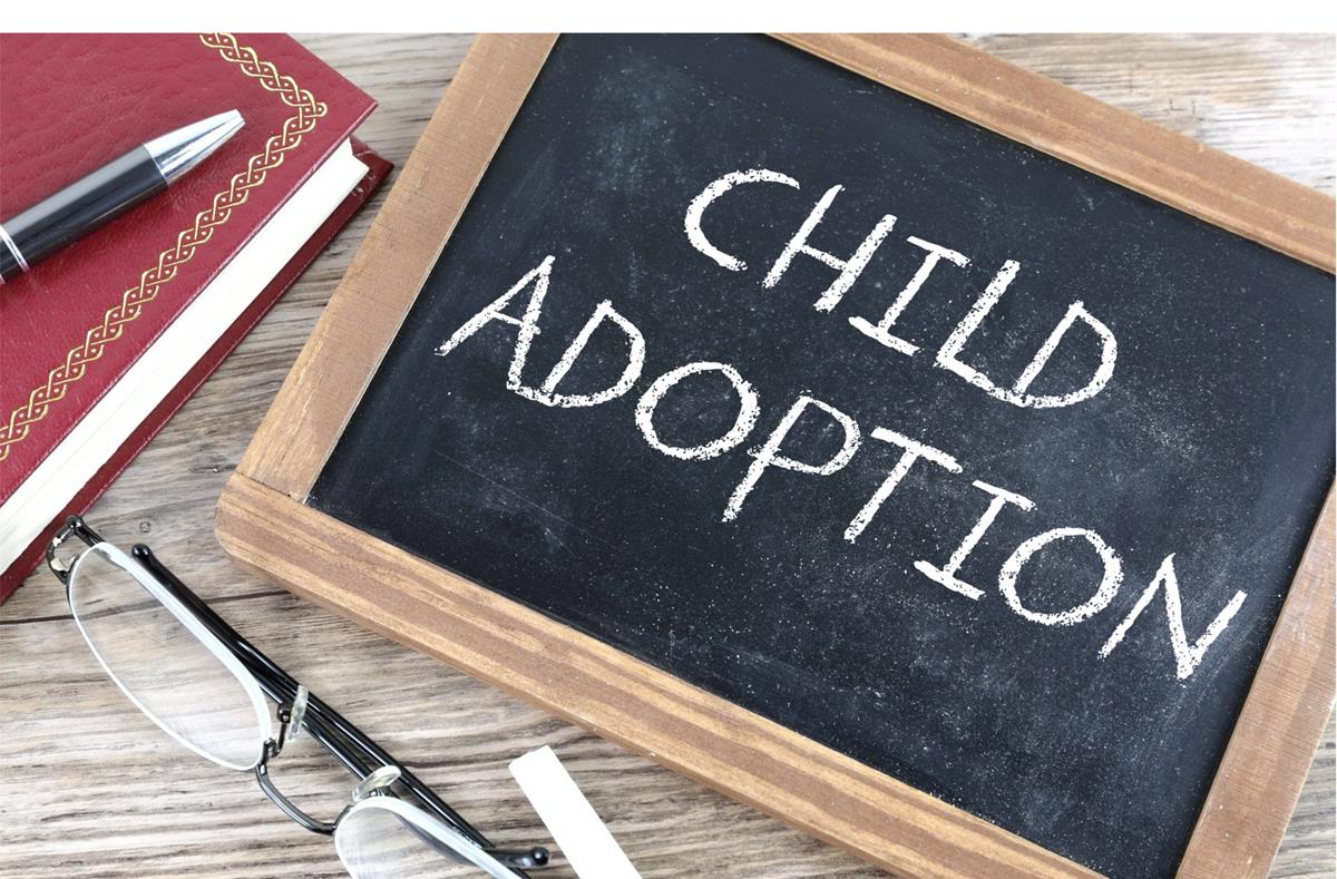 A black chalkboard written with the words " Child Adoption" on it alongside a book, pen, spectacles, and white chalk | Photo: Picpedia.org/Creative Commons 3 - CC BY-SA 3.0/Alpha Stock Images/Nick Youngson
