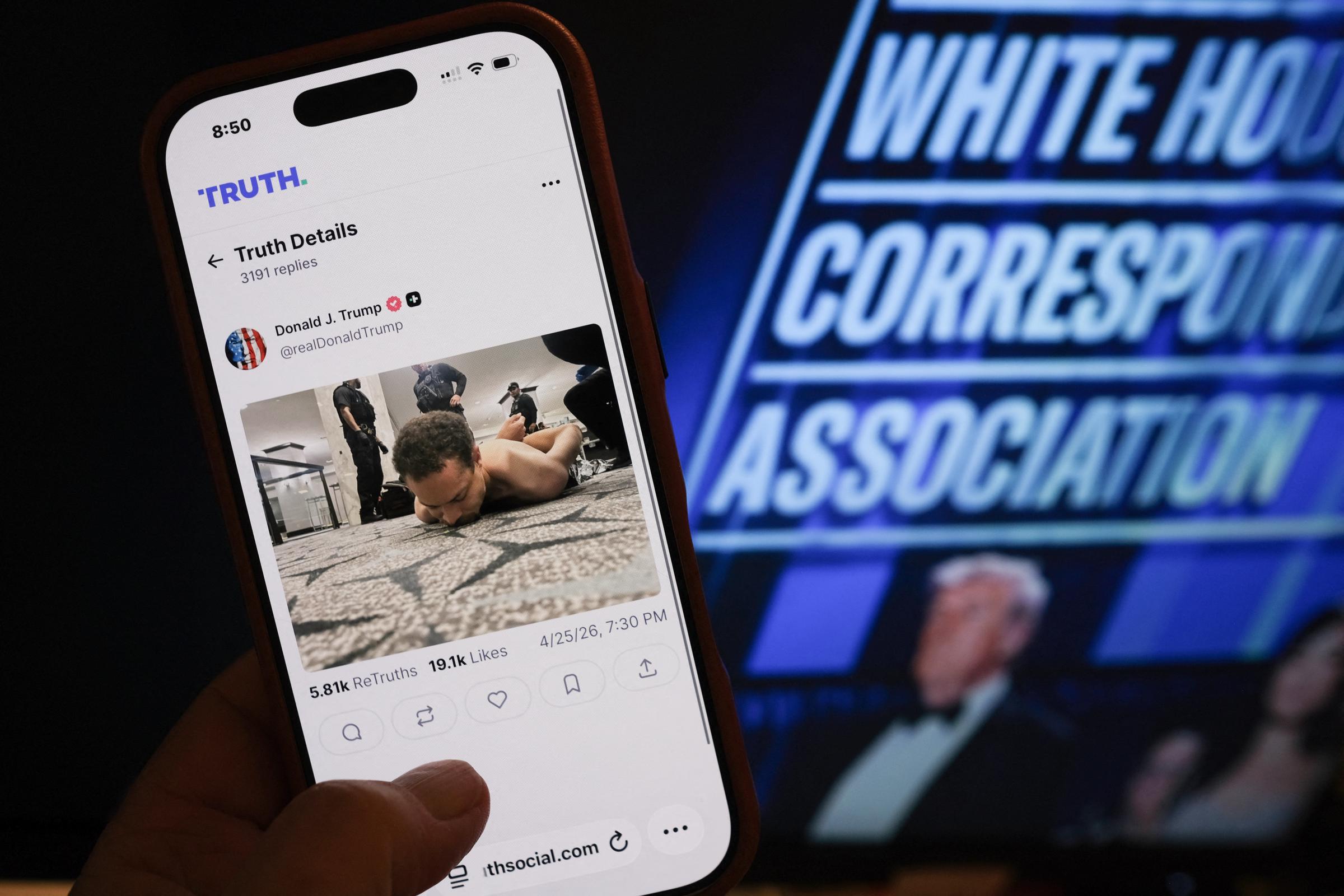 This illustration photo taken in Los Angeles shows a phone with a Truth Social post by Donald Trump displaying an image of the alleged suspect in a shooting incident at the White House Correspondents' Dinner on the ground after being apprehended on April 25, 2026 | Source: Getty Images