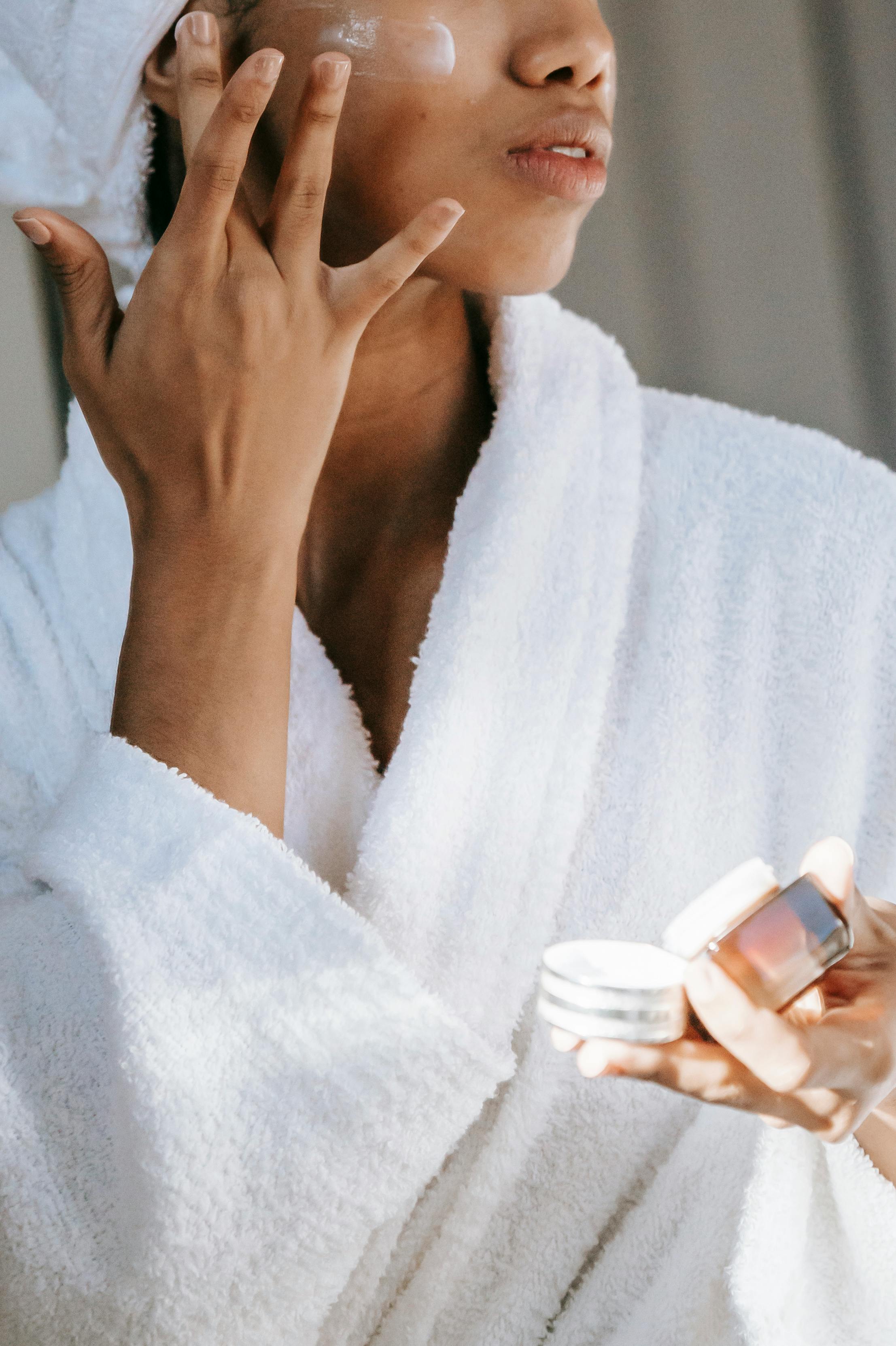 A woman fresh out of the shower, moisturizing her face | Source: Pexels