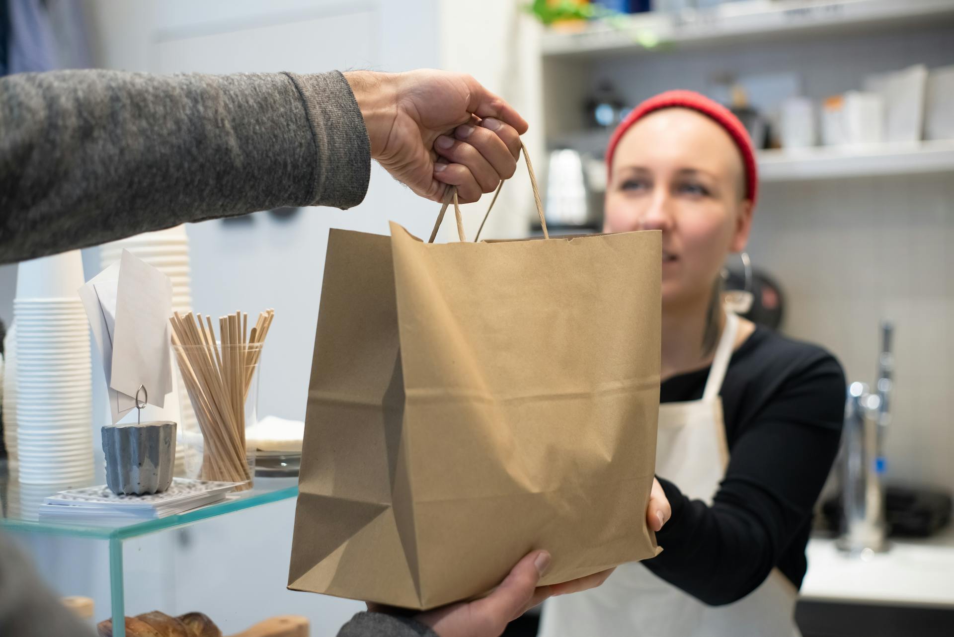 A restaurant worker handing a brown bag to a customer | Source: Pexels