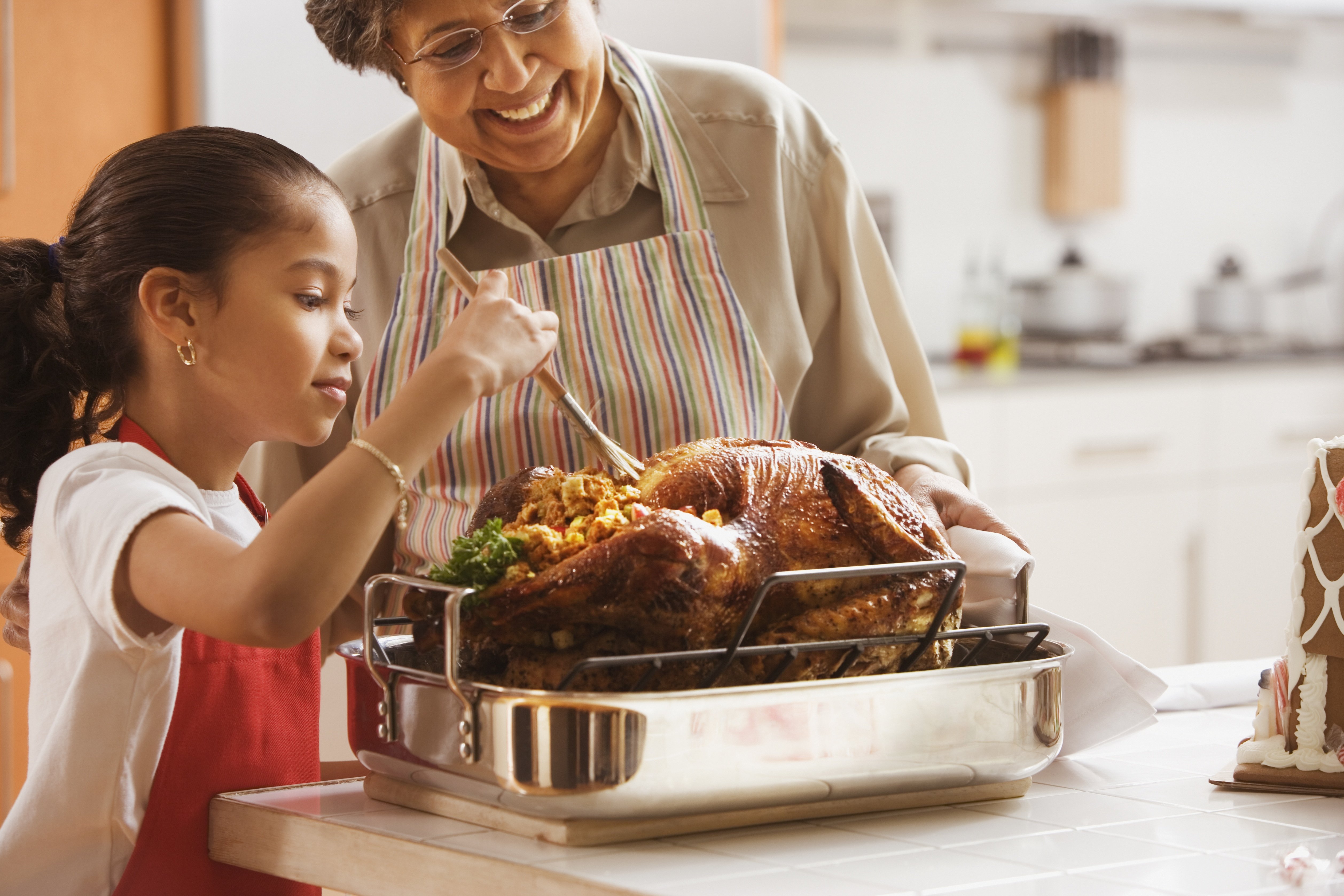 little girl cooking turkey with mom |Photo: Getty Images