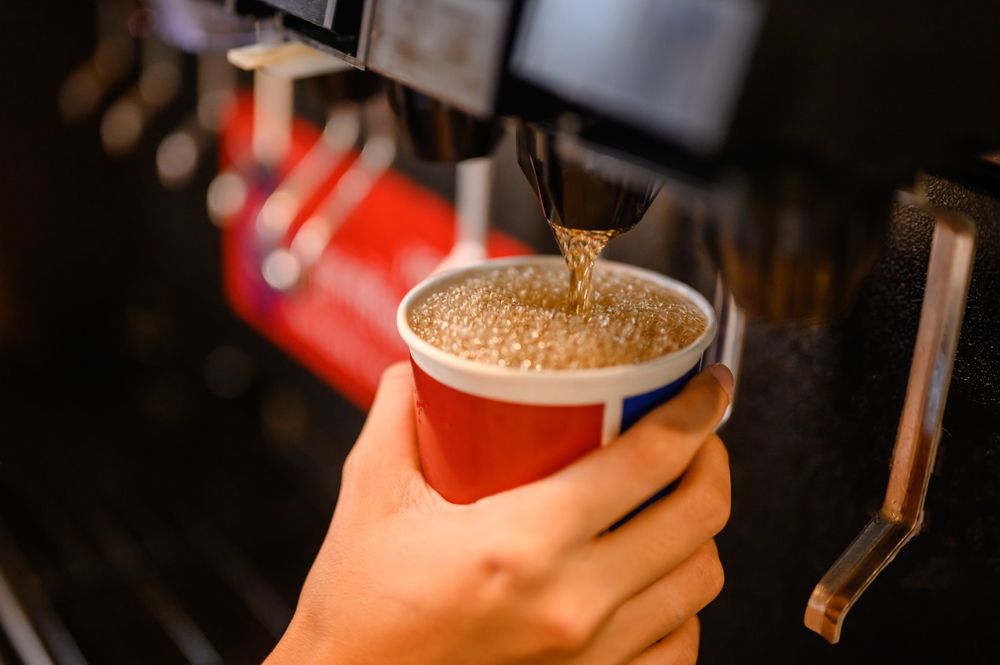 An individual pouring a cold beverage using a soda fountain. │Source: Shutterstock