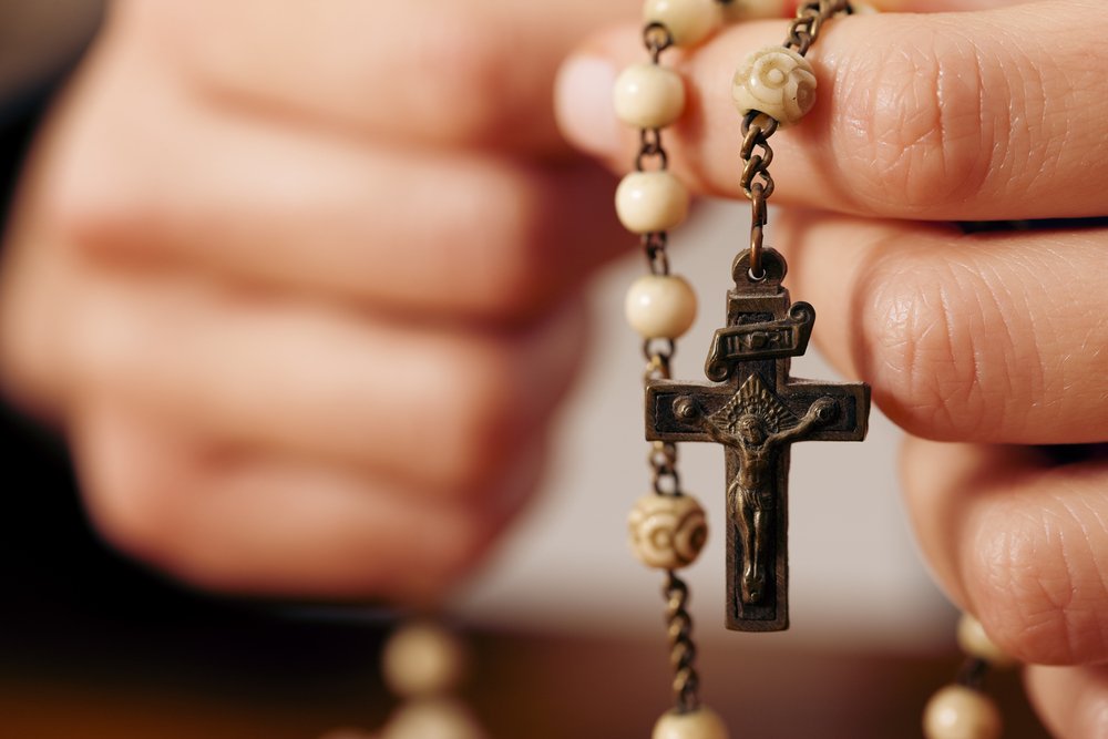 Manos con un rosario. Fuente: Shutterstock
