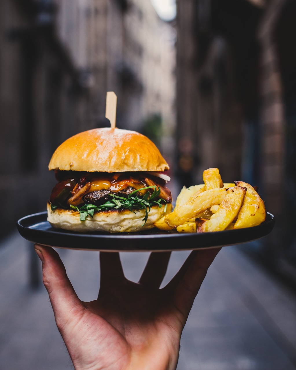 A waiter about to serve a plate with a burger and fries | Source: Pixabay